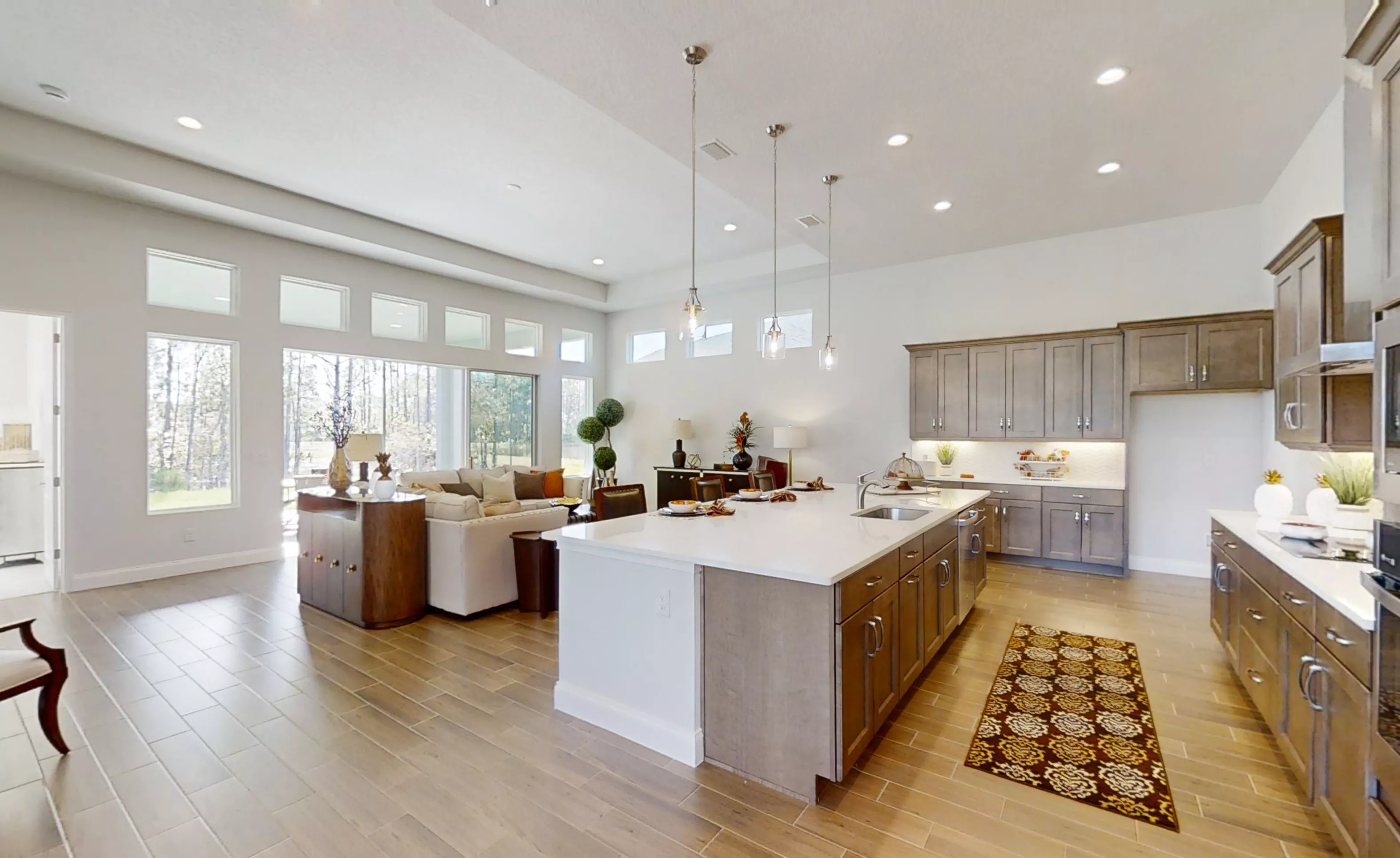 Charlotte plan kitchen in Woodhaven with center island, wood cabinets, white countertops, and open-plan living area.