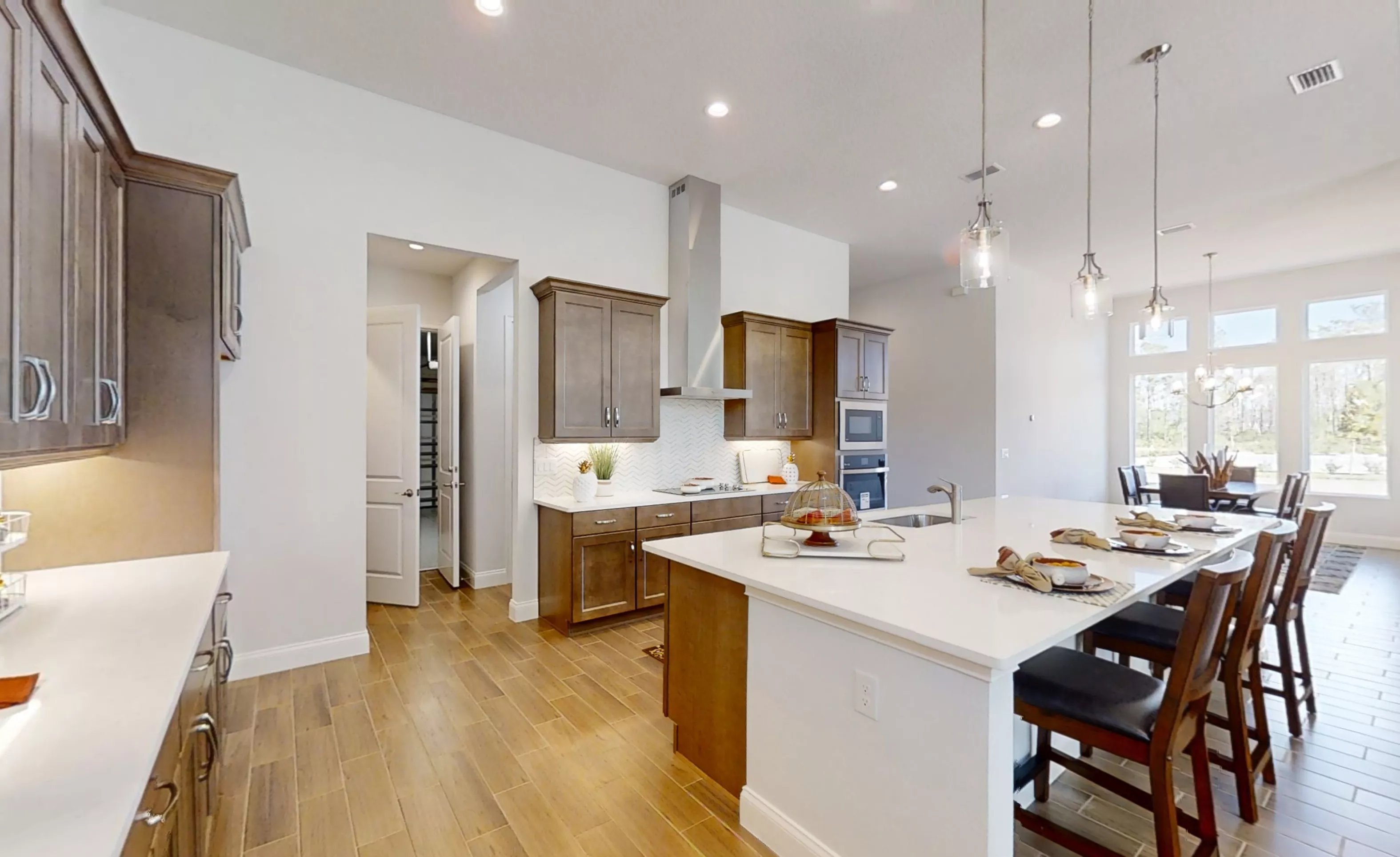 Kitchen of the Charlotte plan featuring brown wood cabinets, white countertops, a central island, and wood-look tile floors.