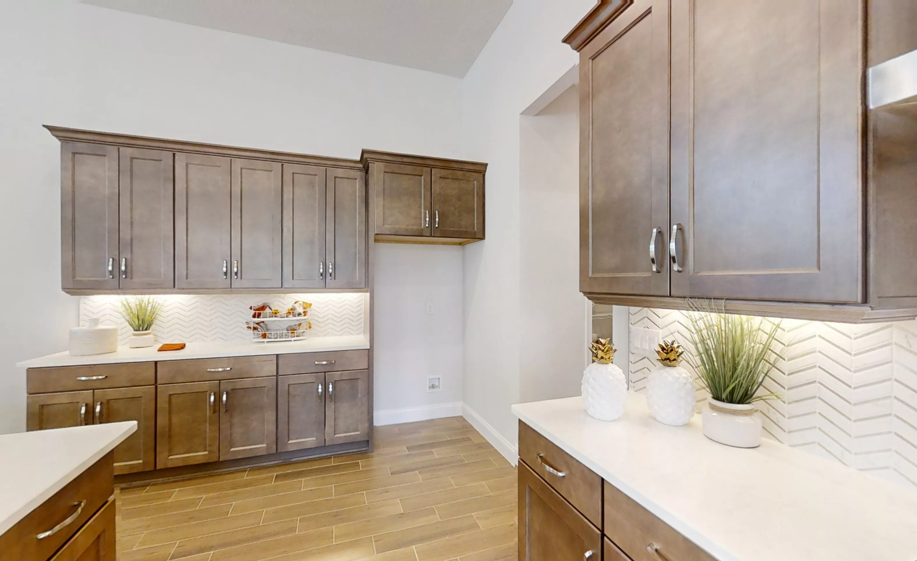 Charlotte plan kitchen featuring dark wood cabinets, white countertops, and a white herringbone tile backsplash.