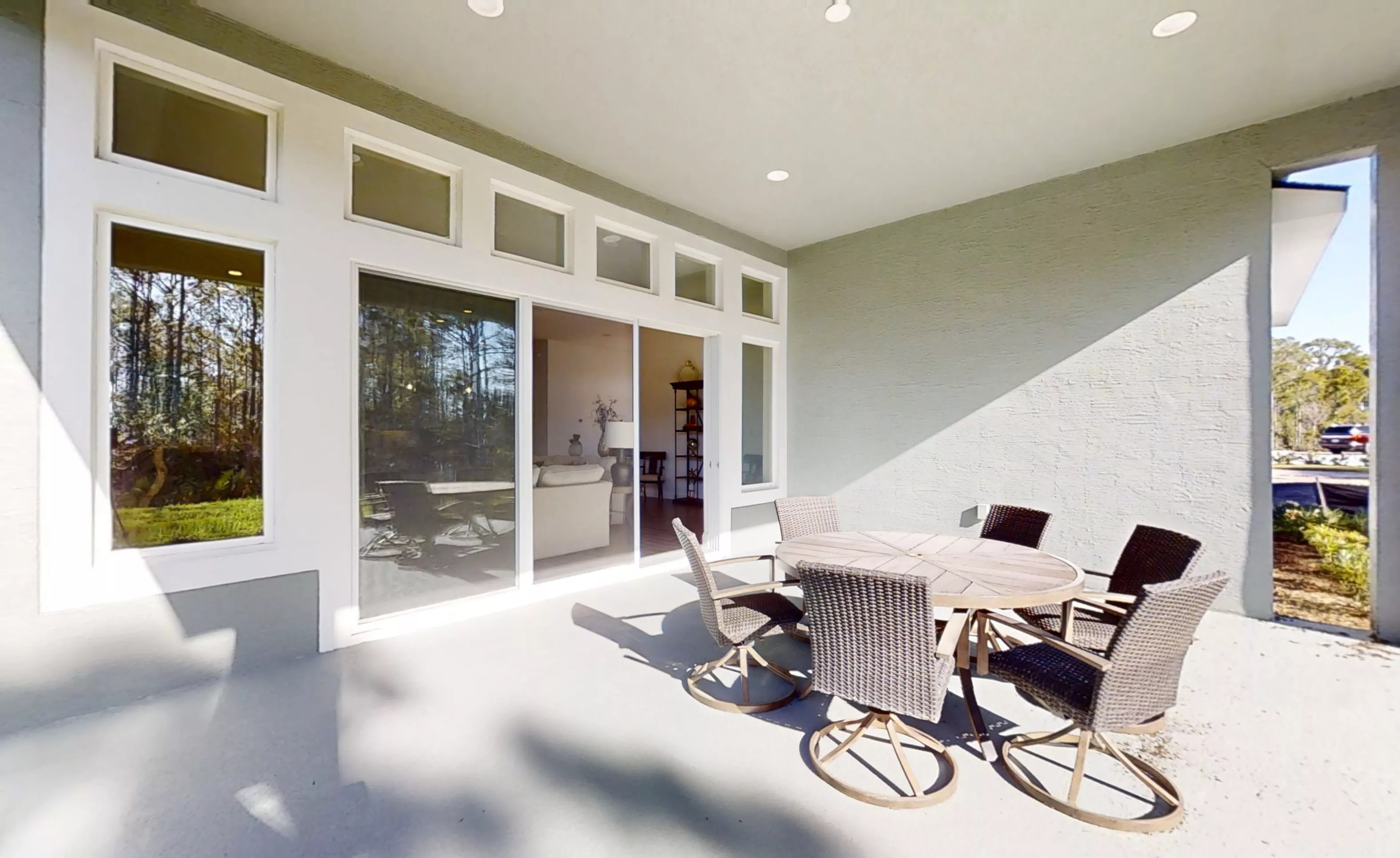 Covered lanai in Woodhaven featuring a circular patio table with four wicker chairs and sliding glass doors to the home.