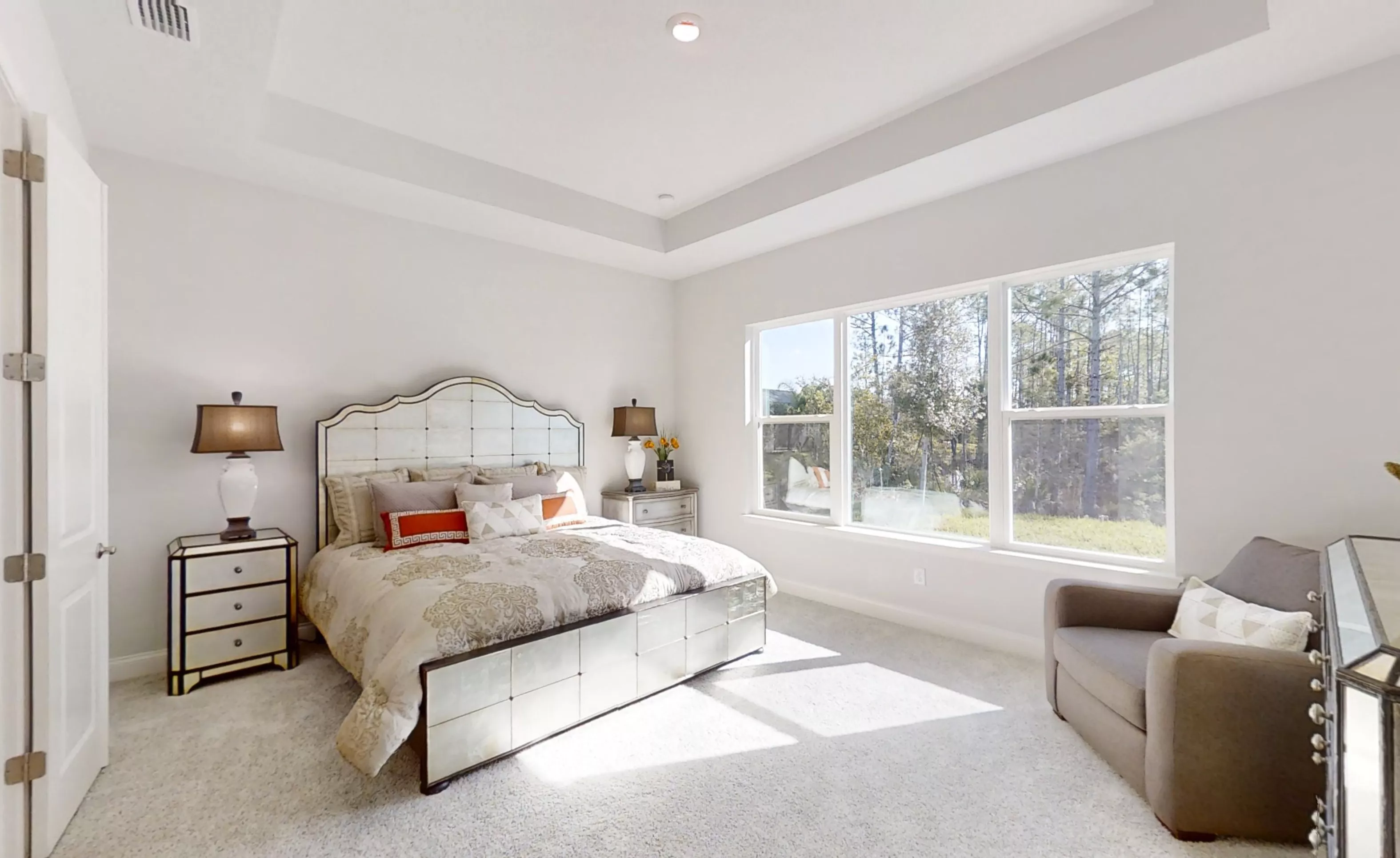 Primary bedroom in the Charlotte plan featuring a tray ceiling, light gray walls, carpet, and a wall of windows.