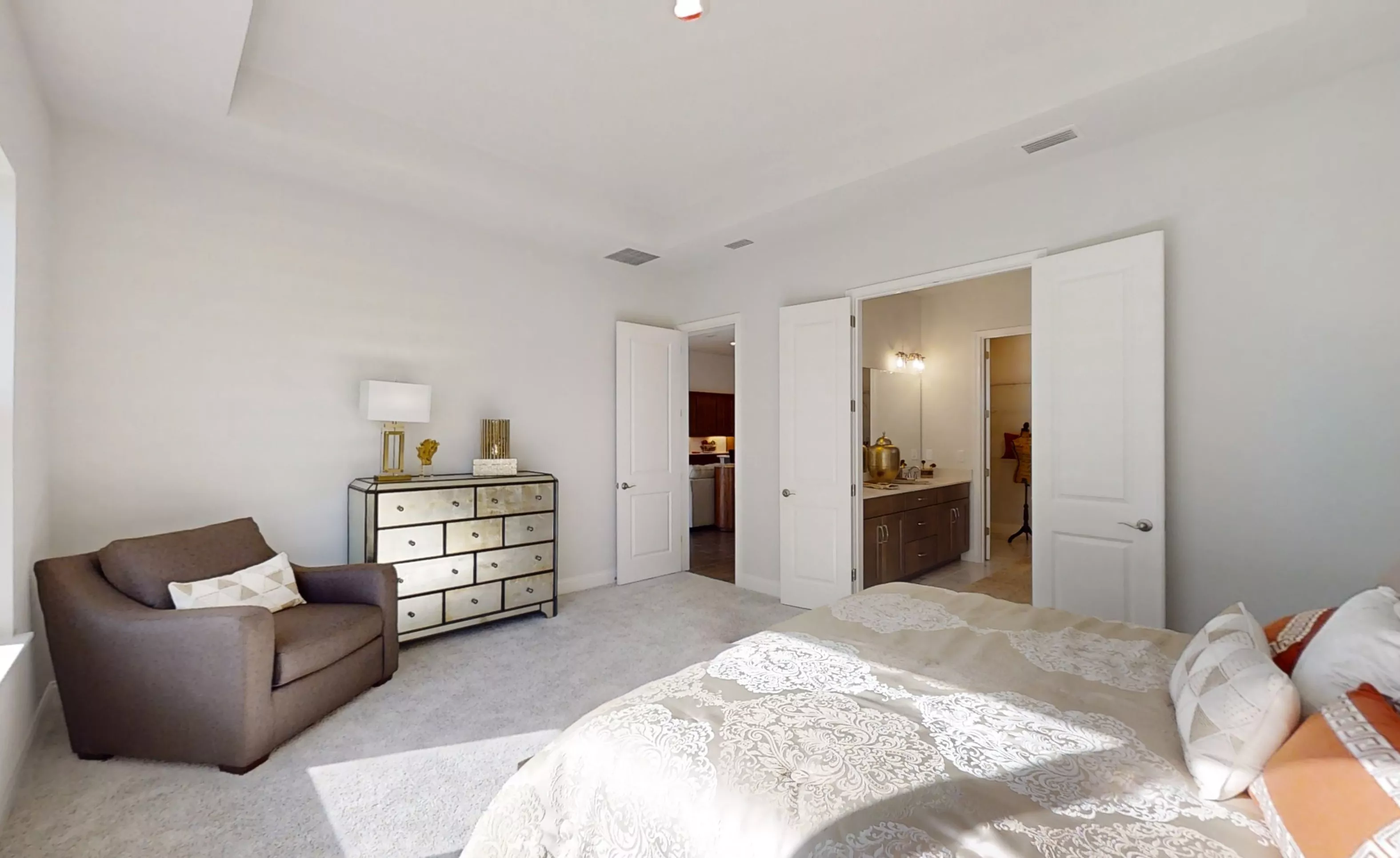 Primary bedroom in the Charlotte plan featuring a tray ceiling, carpeted floor, an armchair, and a mirrored dresser.