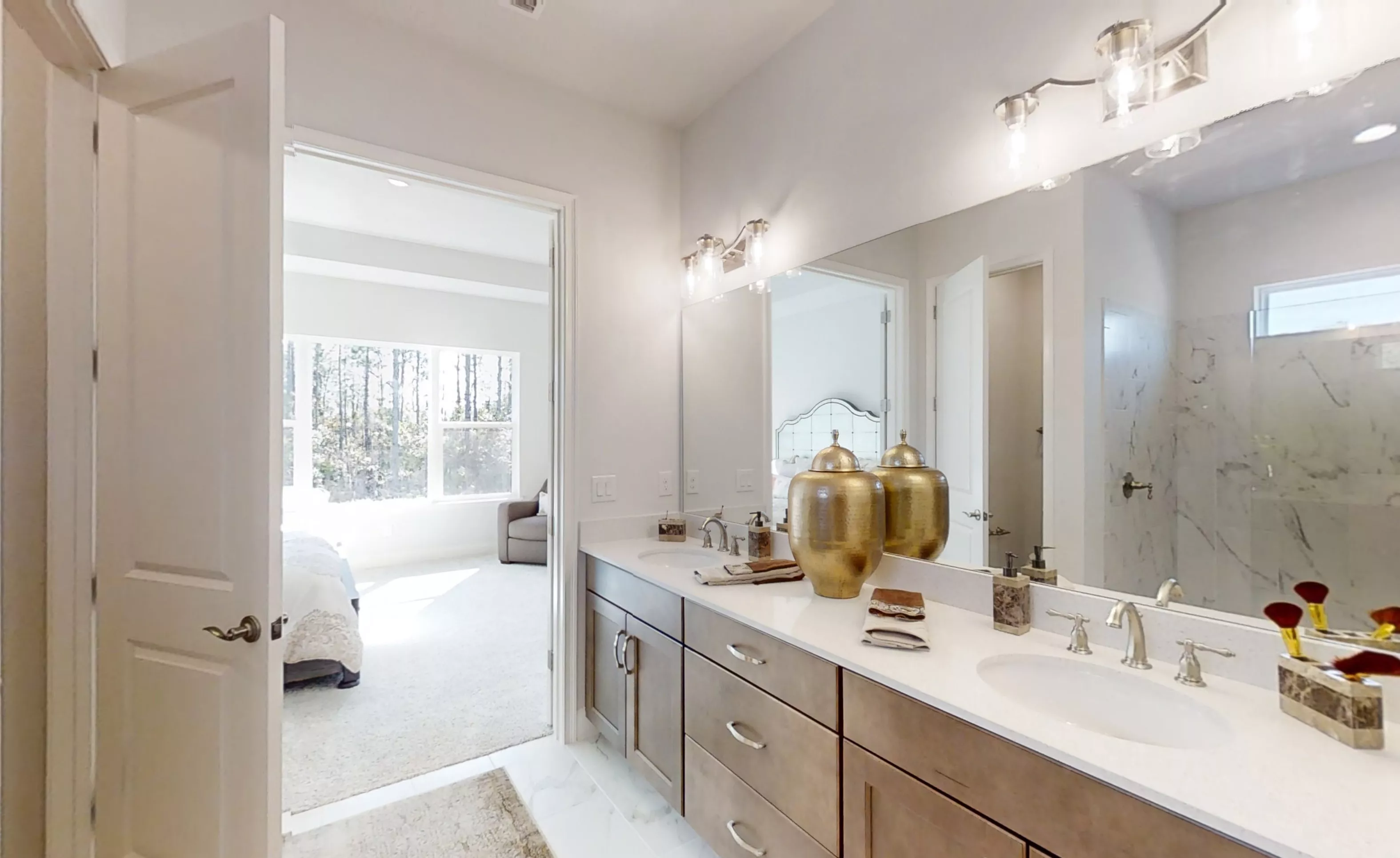 Primary bath with double-sink wood vanity, white countertop, large mirror, and view into the adjacent bedroom.