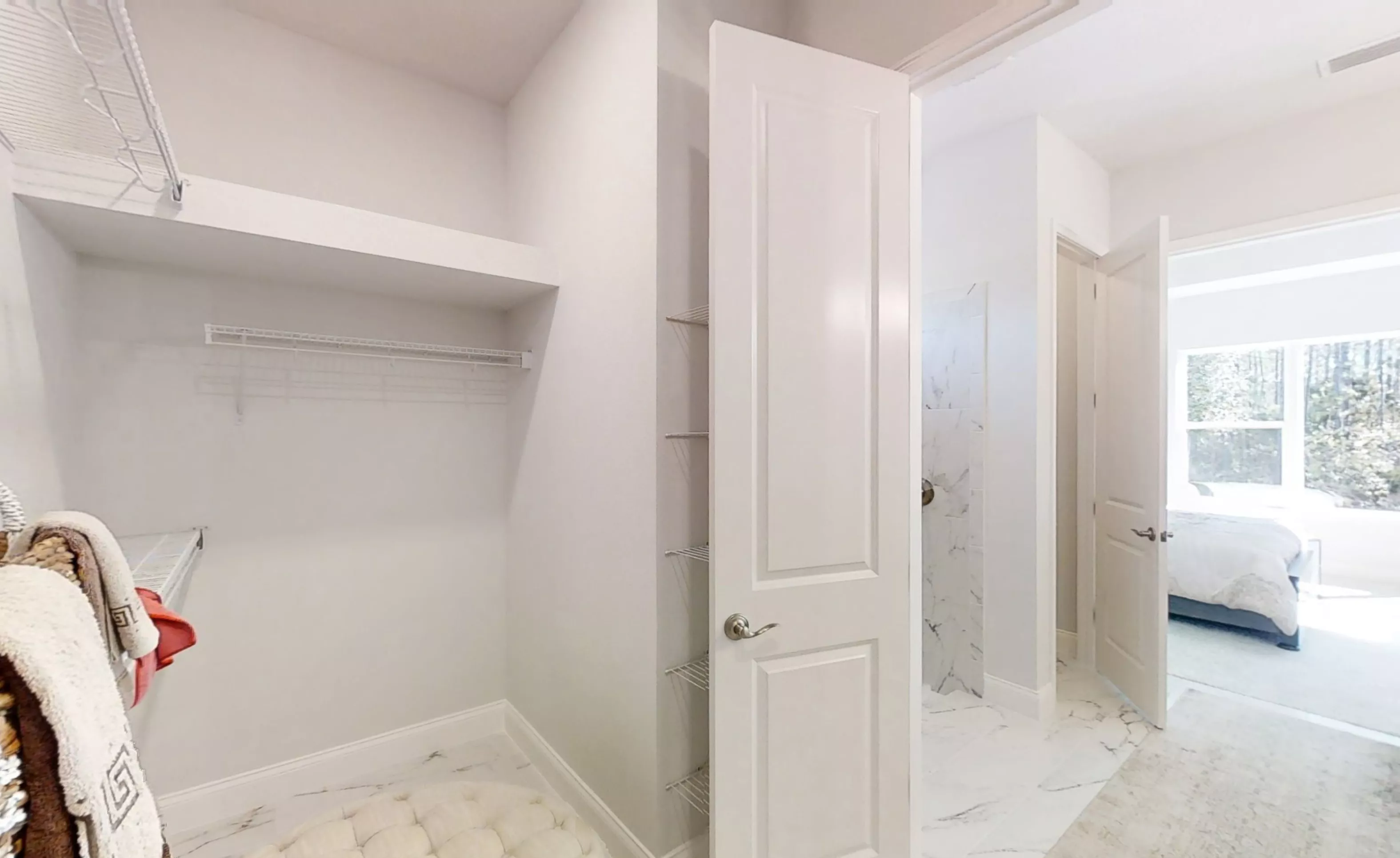 Walk-in closet in the Charlotte plan featuring white shelving, marble-look flooring, and a view into the bedroom.