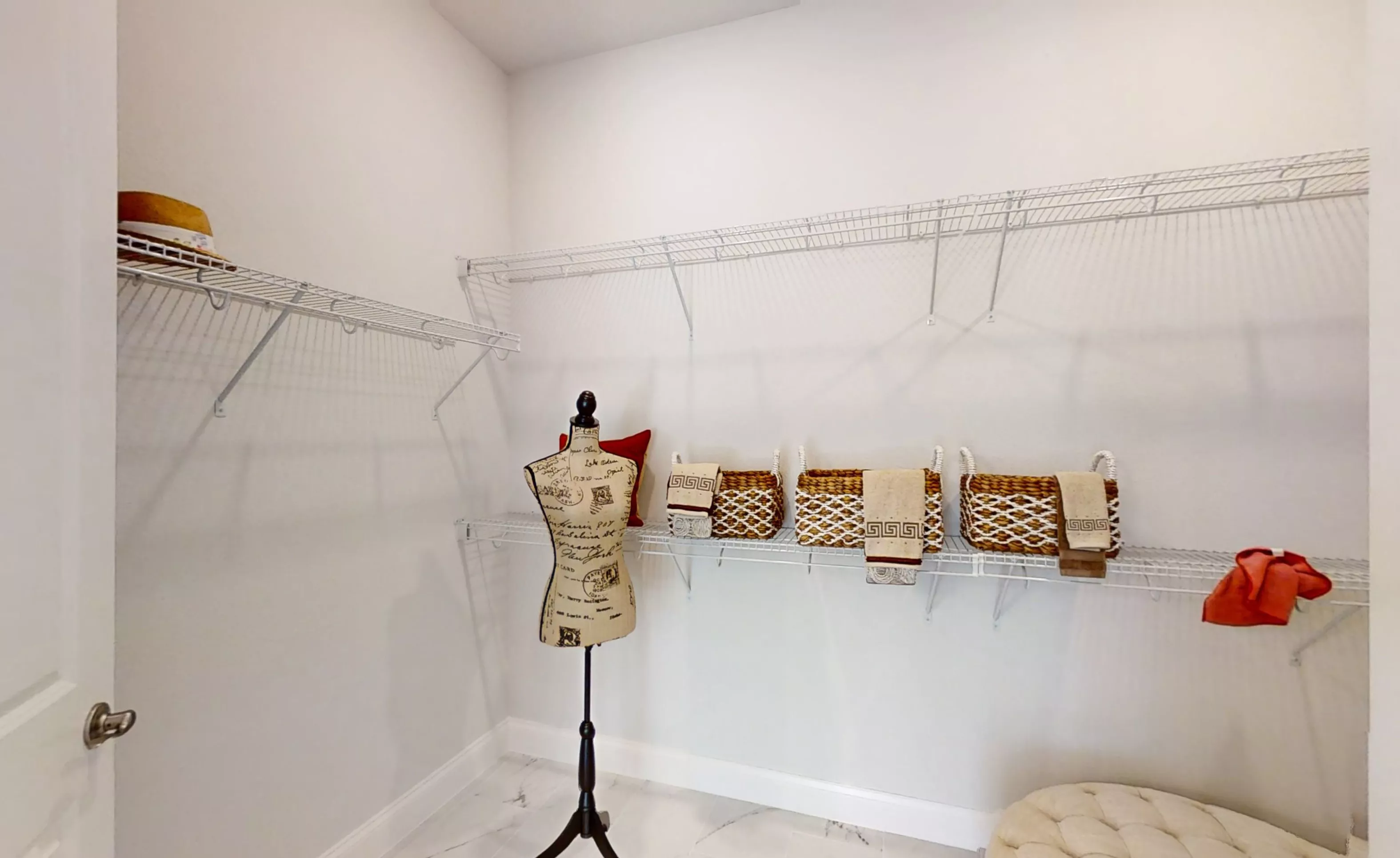 Walk-in closet in the Charlotte plan featuring white wire shelving, white walls, and light marble-look tile flooring.