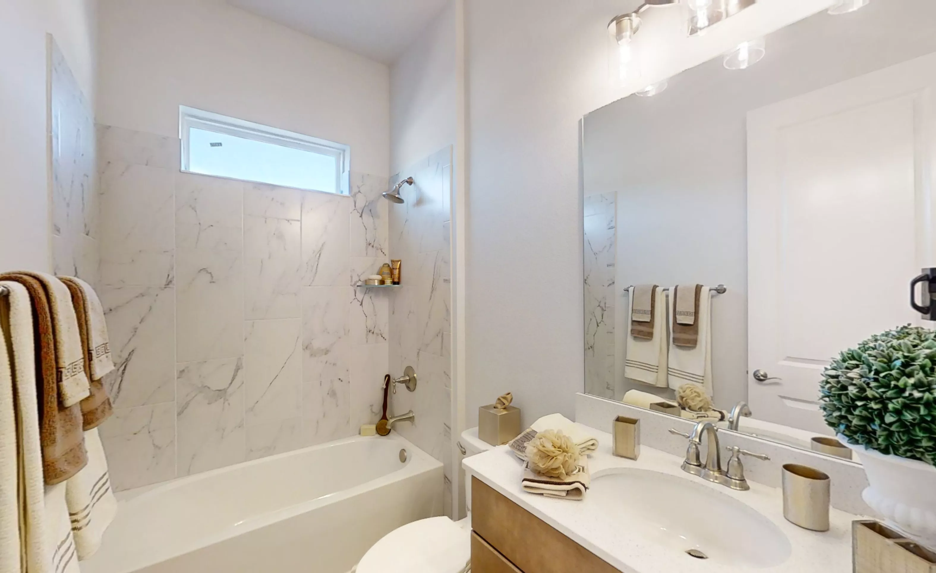 Secondary bathroom in the Charlotte plan featuring a tub-shower combination with white marble-look tile and wood vanity.