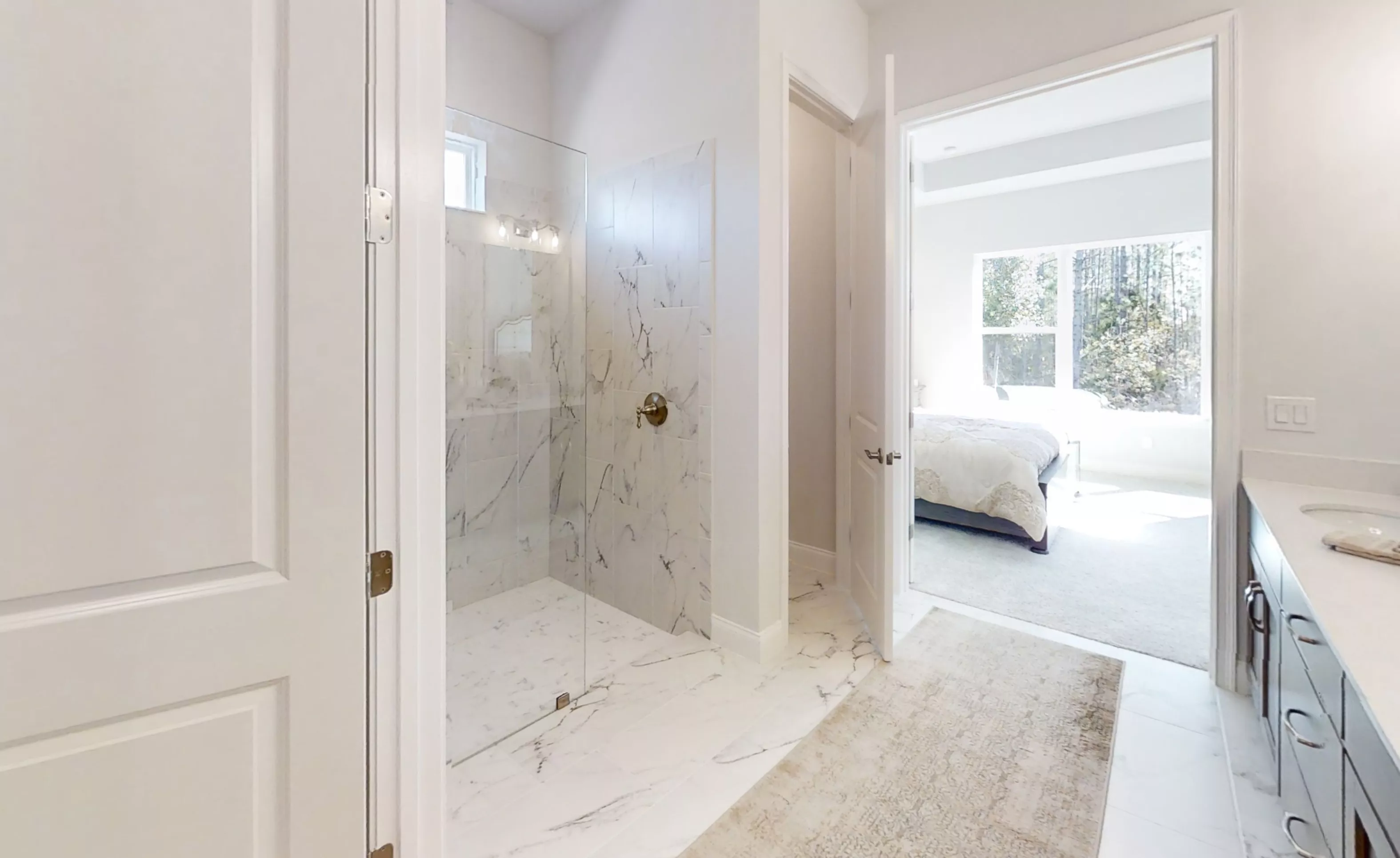 Primary bath of the Charlotte plan featuring a glass-enclosed shower with marble-look tile, leading to the bedroom.