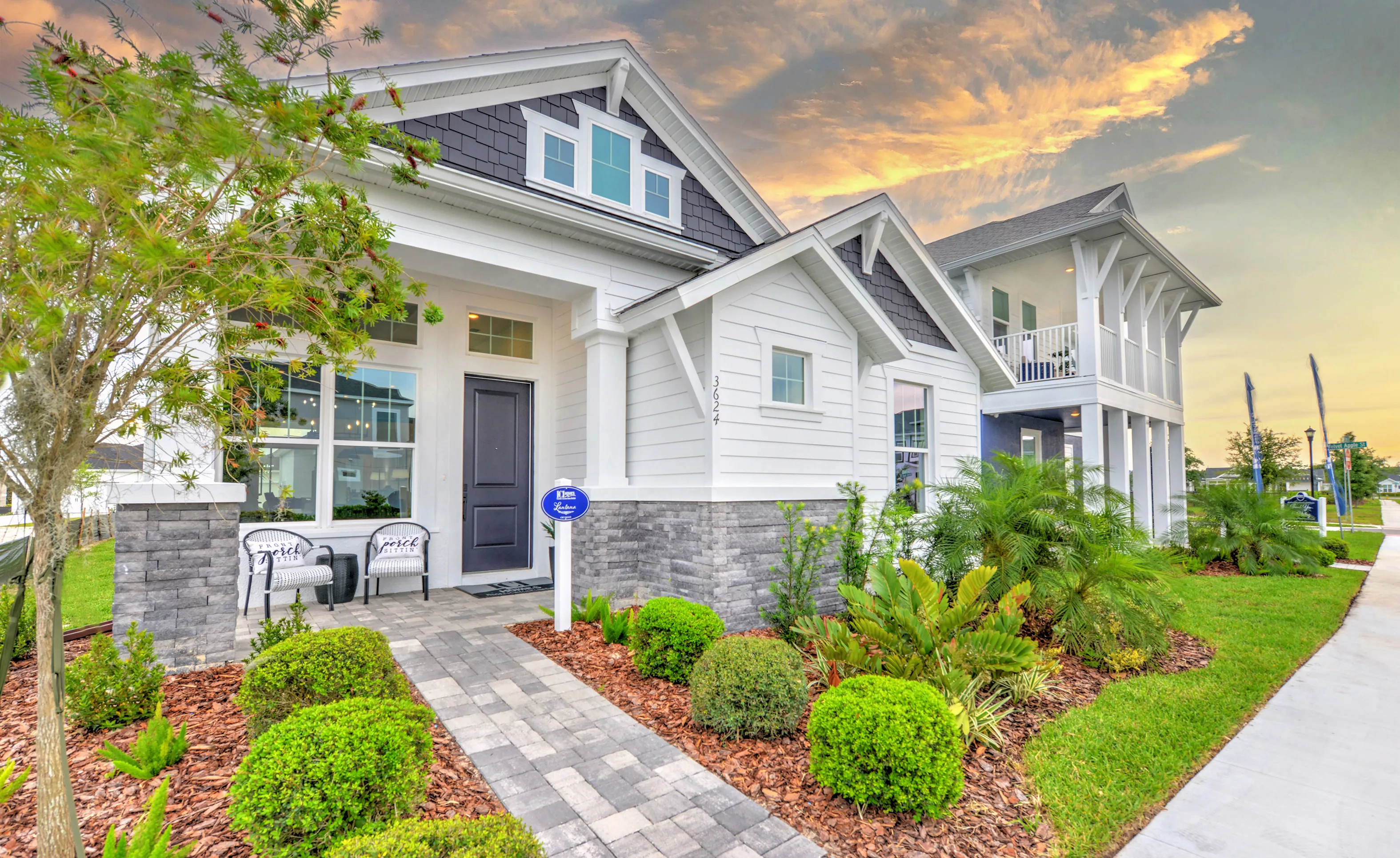Front exterior of the Lantana home plan in Persimmon Park, featuring white siding, grey stone accents, and a front porch.