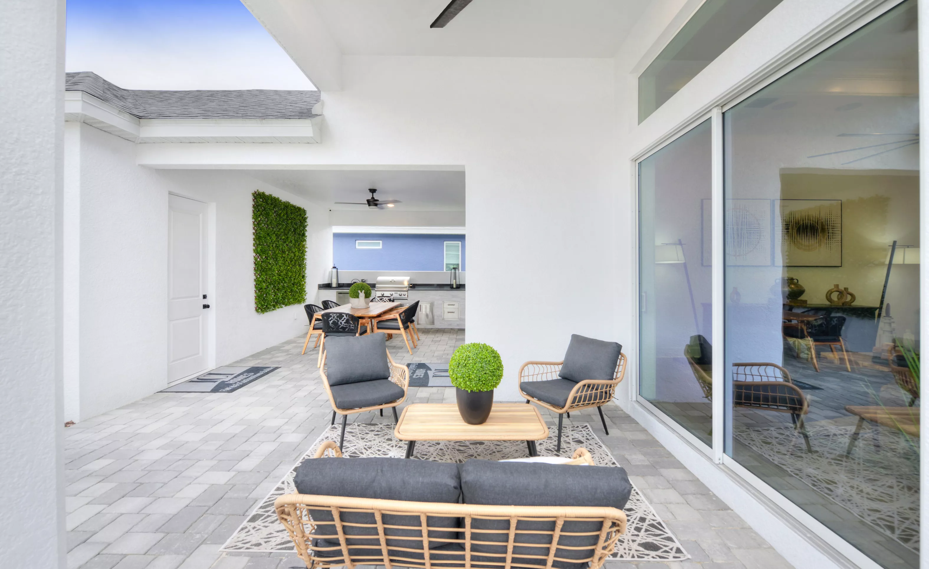 Covered patio of the Lantana plan featuring a paver floor, outdoor seating area, and a separate outdoor kitchen space.