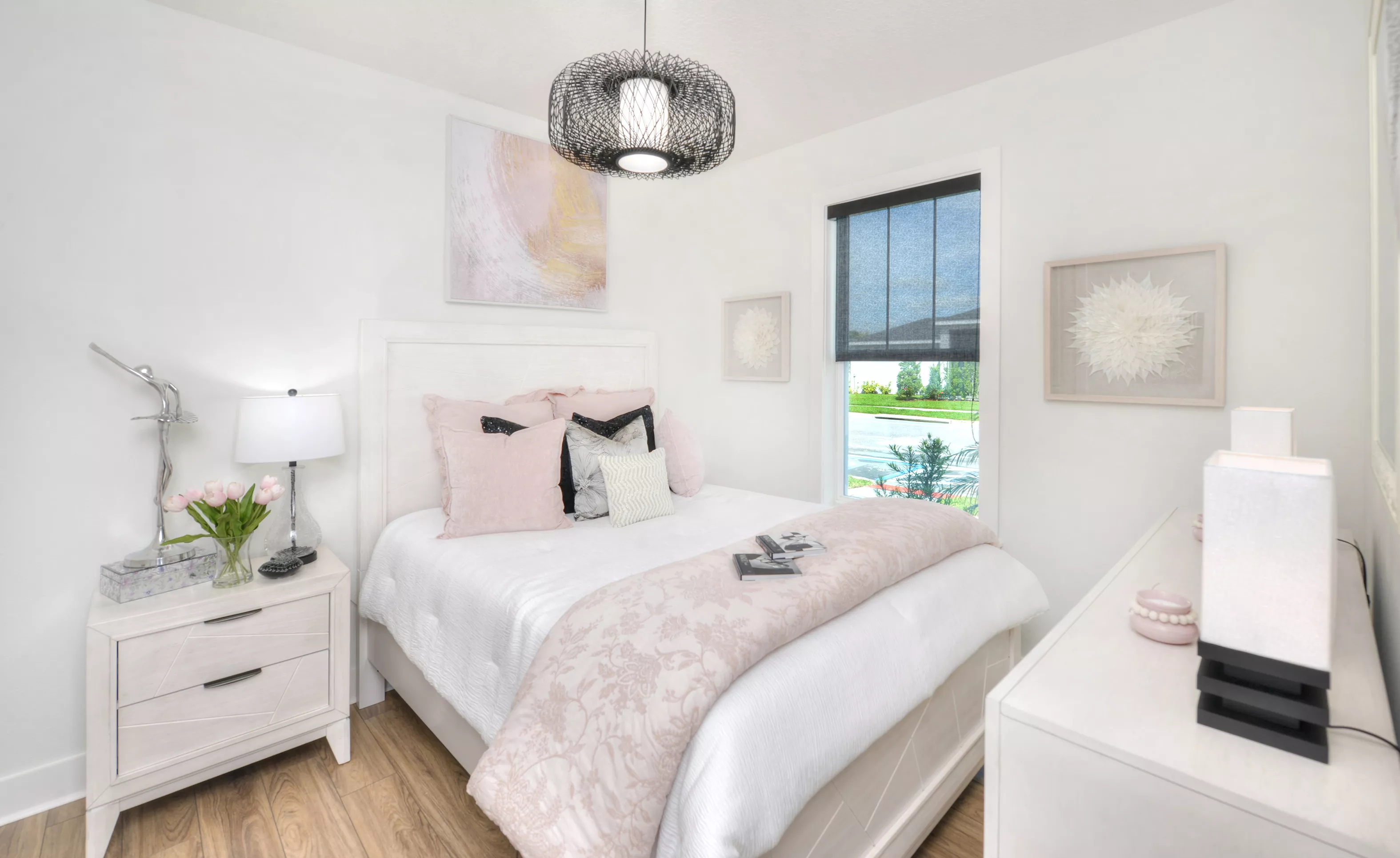Secondary bedroom in the Lantana plan with white furniture, wood-look flooring, pink bedding, and a dark metal pendant light.