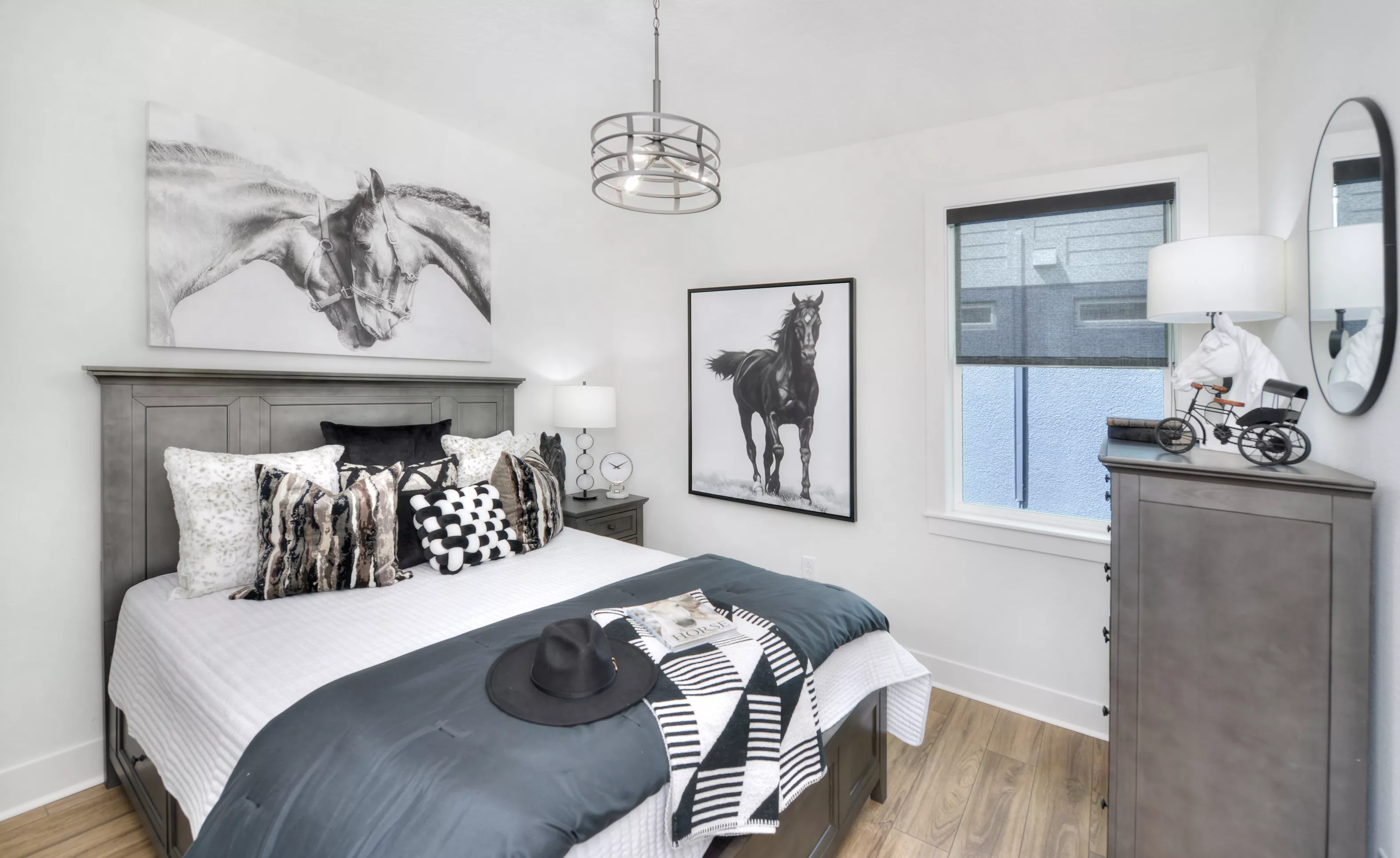 Secondary bedroom featuring a bed with gray frame, horse-themed artwork, modern pendant lighting, and wood-look flooring.