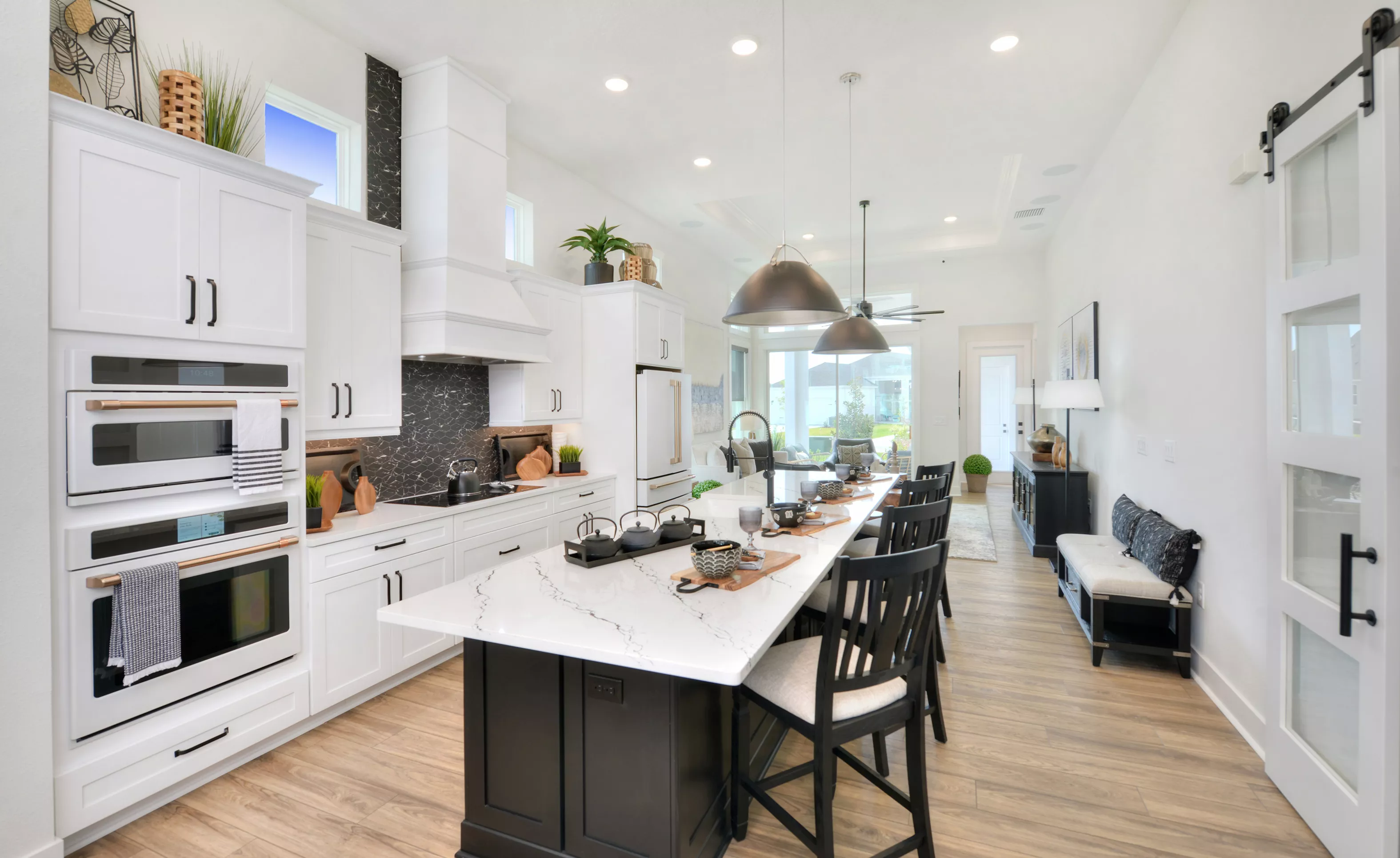 Kitchen in the Lantana plan with white cabinetry, a black kitchen island, quartz countertops, and a black tile backsplash.