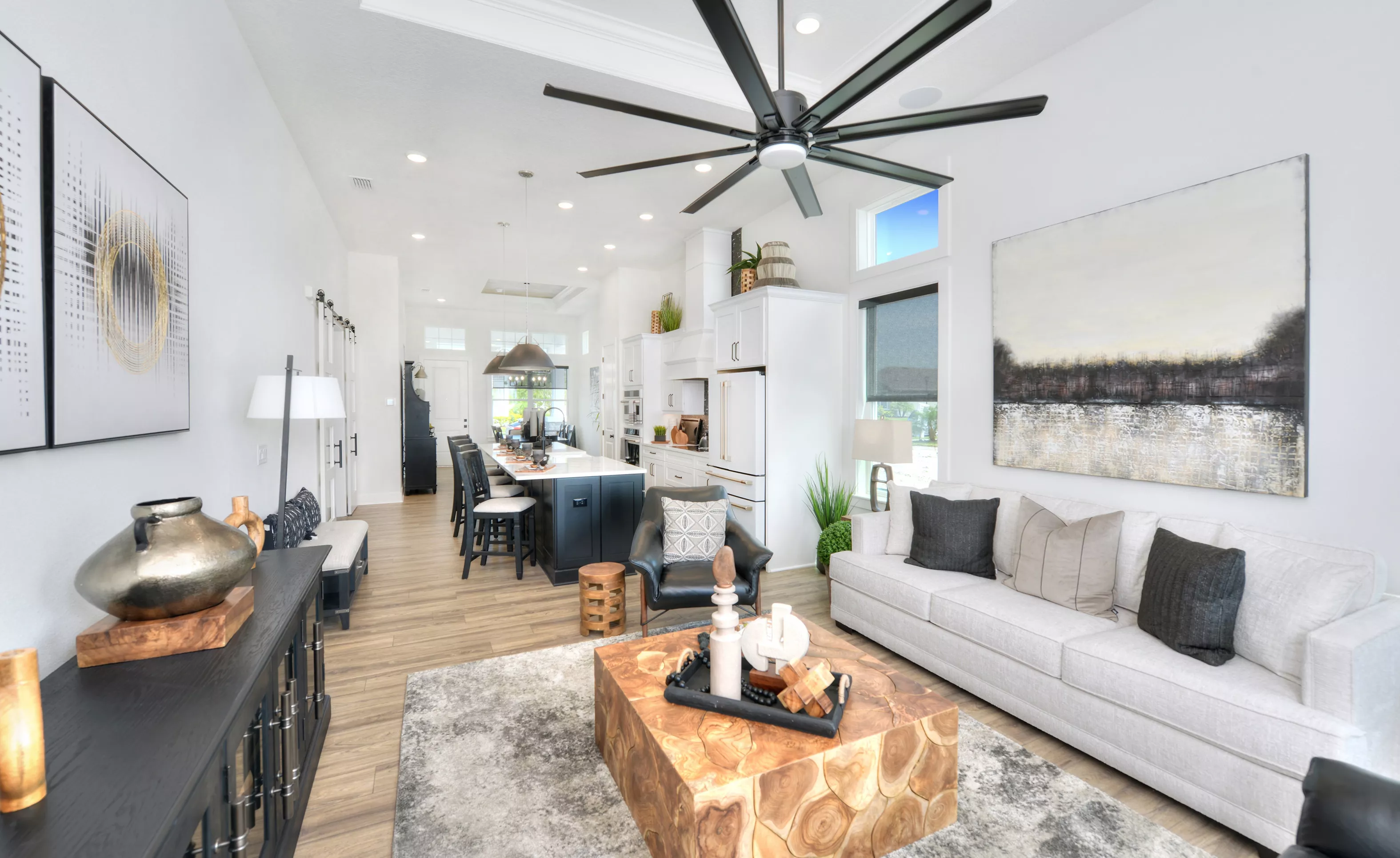 Lantana plan living room in Persimmon Park featuring white furniture, a large wooden coffee table, and open kitchen layout.