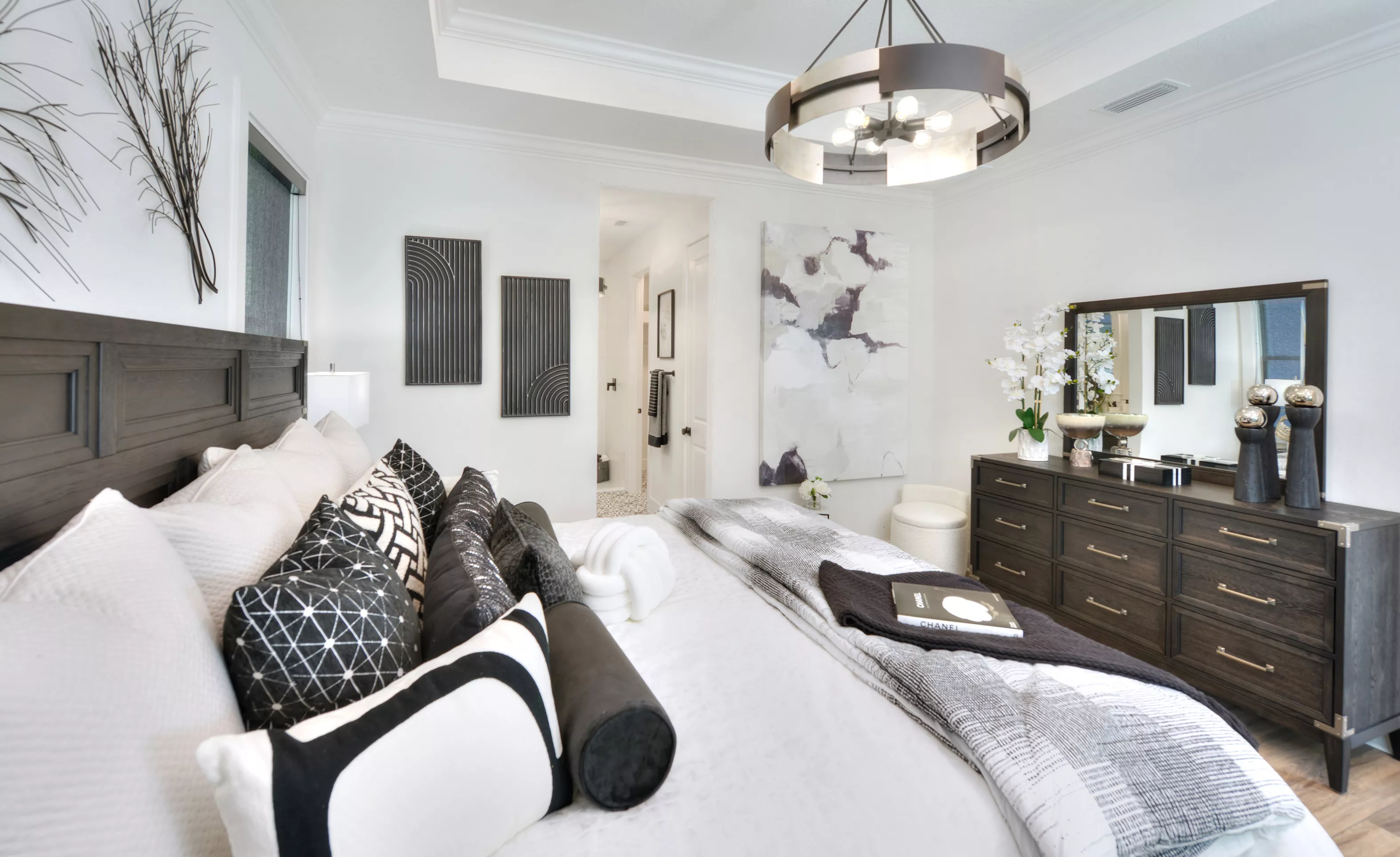 Primary bedroom in the Lantana plan with tray ceiling, dark wood furniture, and black and white decor.