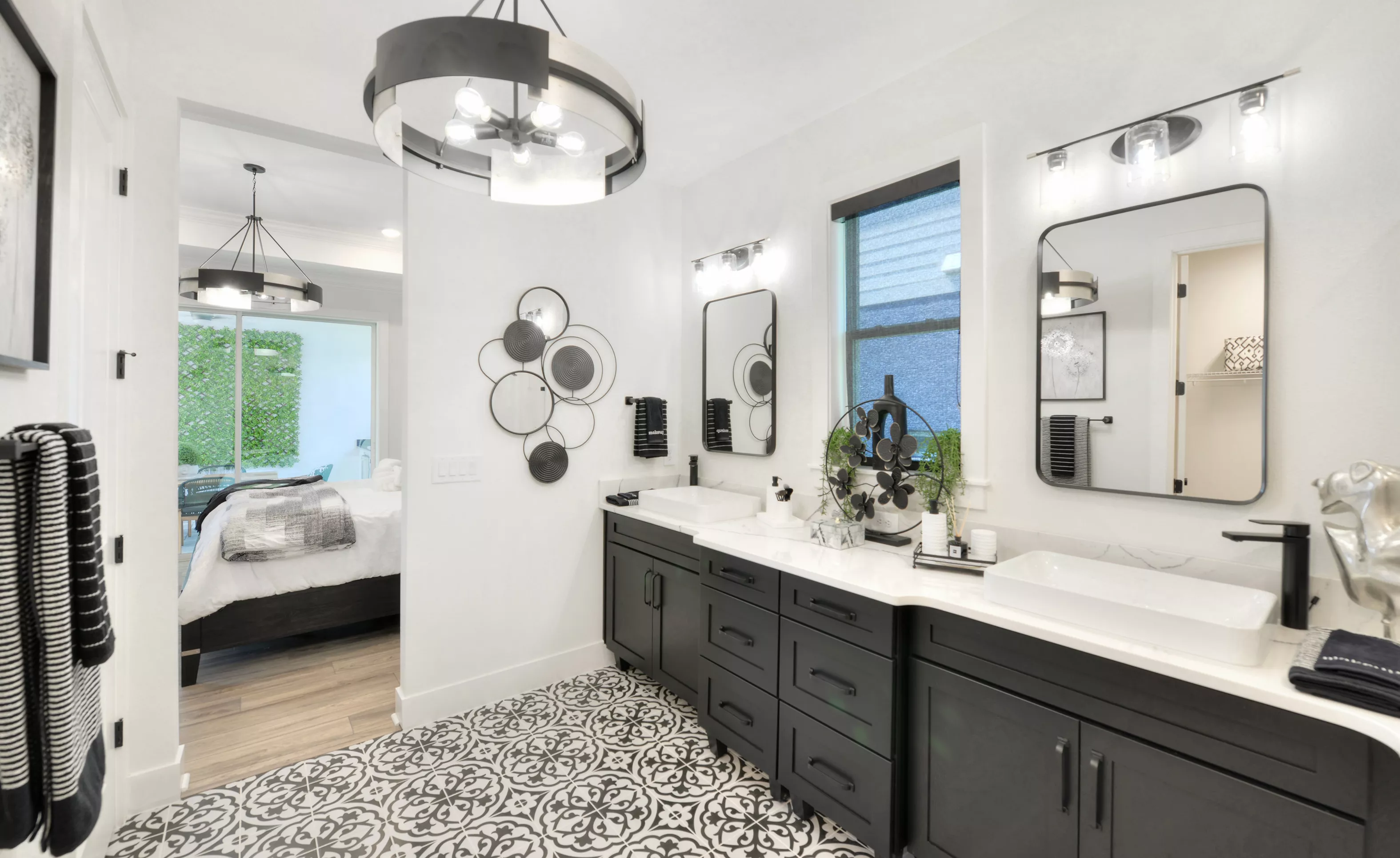 Primary bath in the Lantana plan with dual black vanities, vessel sinks, patterned tile floor, and a view into a bedroom.