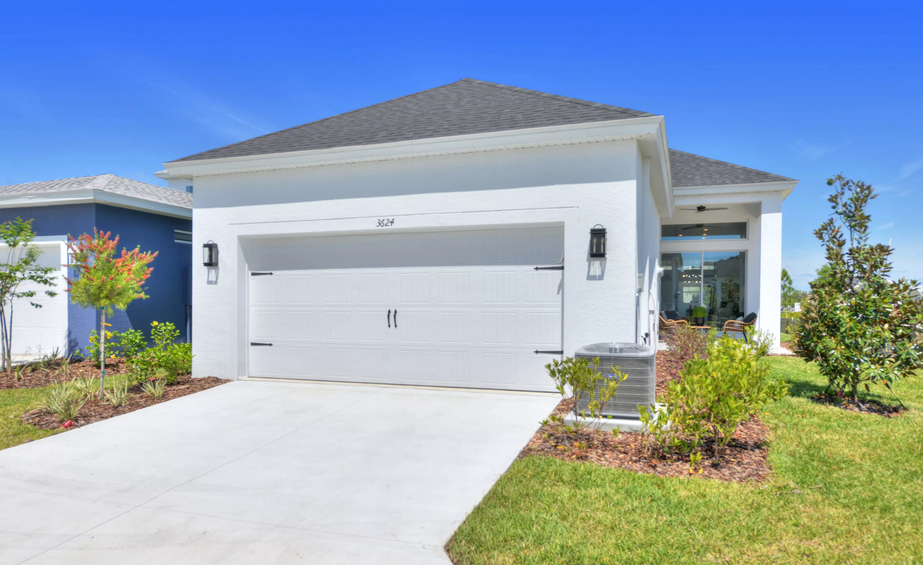 Front exterior of the white Lantana home featuring a two-car garage, concrete driveway, and covered entryway.