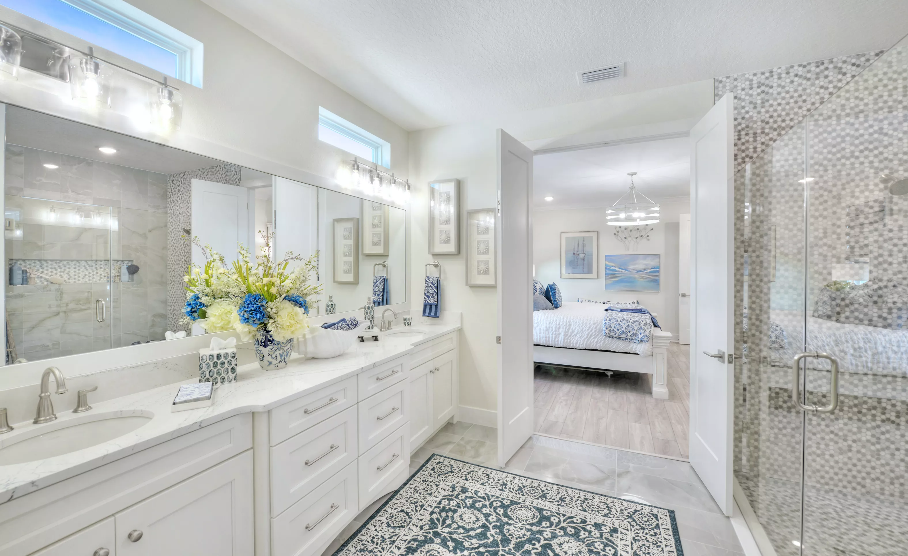 Primary bath in the Azalea plan with white dual vanity, tile floors, walk-in glass shower, and view into the bedroom.