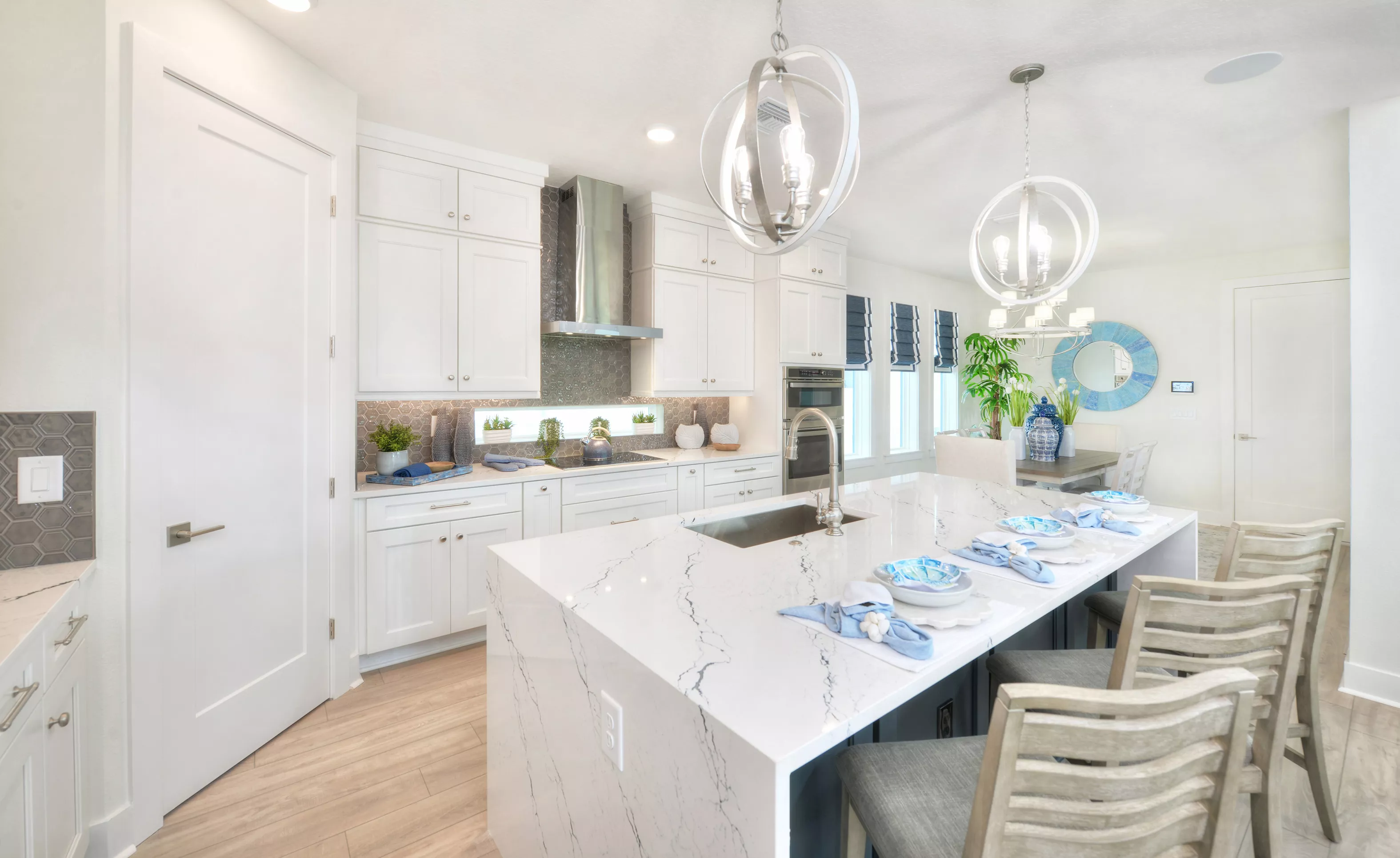 Kitchen in the Azalea plan with a large marble-look island, white cabinets, stainless hood, and orb pendant lighting.