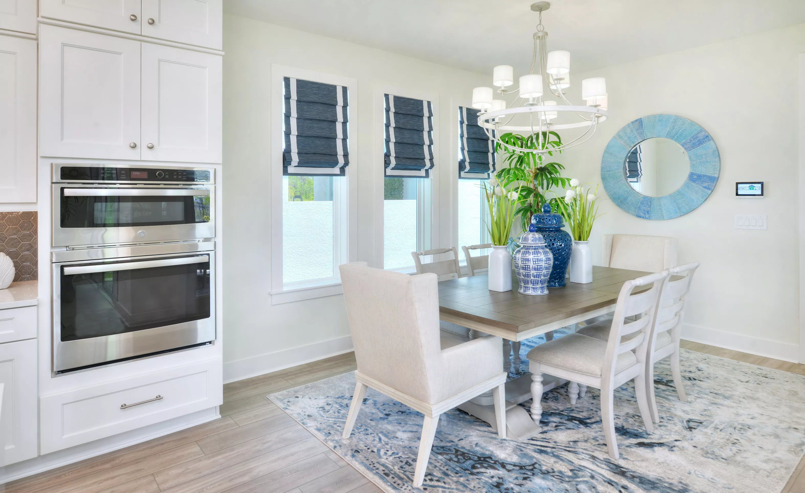Dining room with wood table, upholstered chairs, blue and white decor, and white built-in wall oven in Persimmon Park.