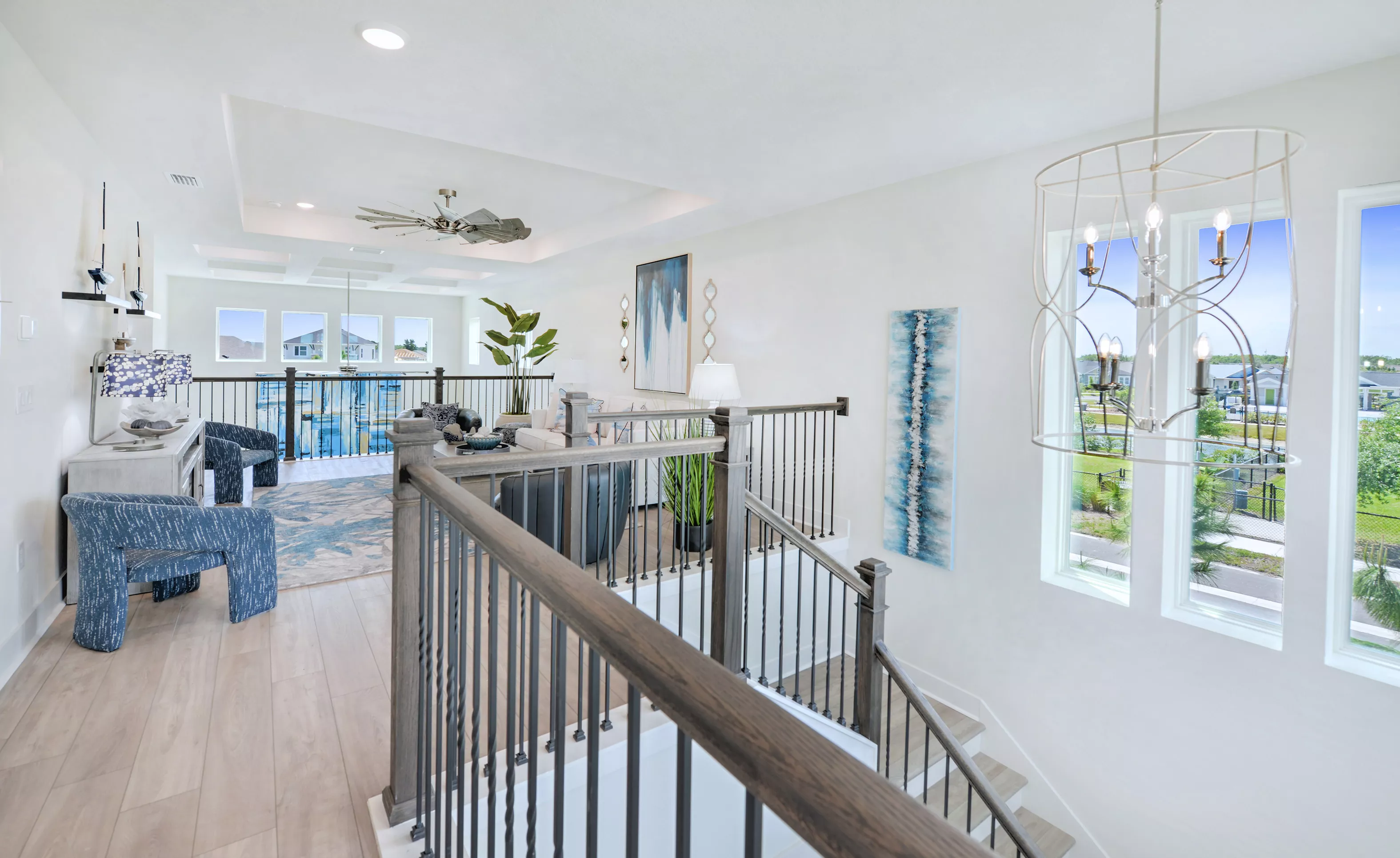 Bonus room in the Azalea plan with wood-look tile floors, tray ceiling, and a staircase with metal spindles.