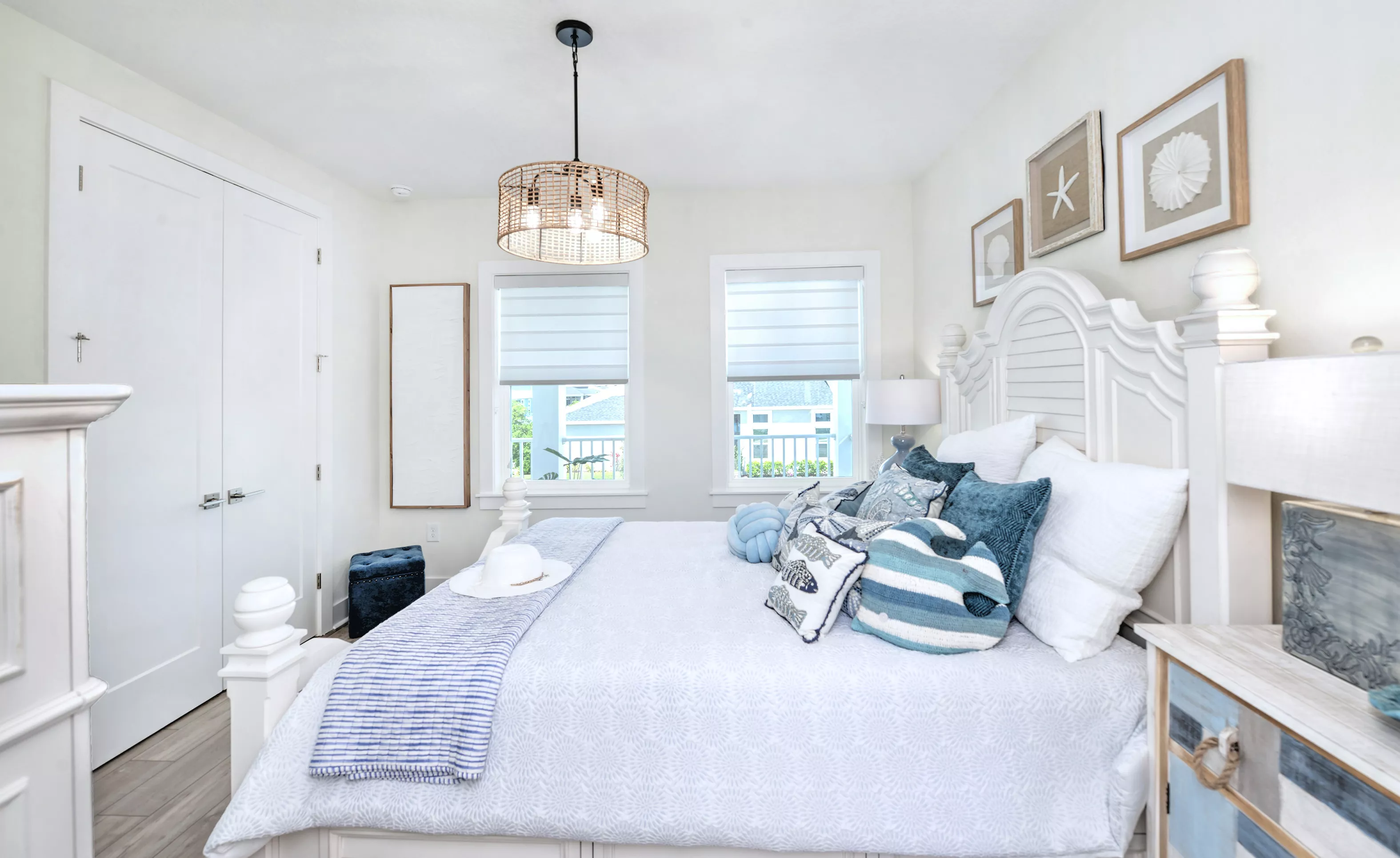 Secondary bedroom in the Azalea plan with a white bed frame, blue and white coastal decor, and a woven pendant light.