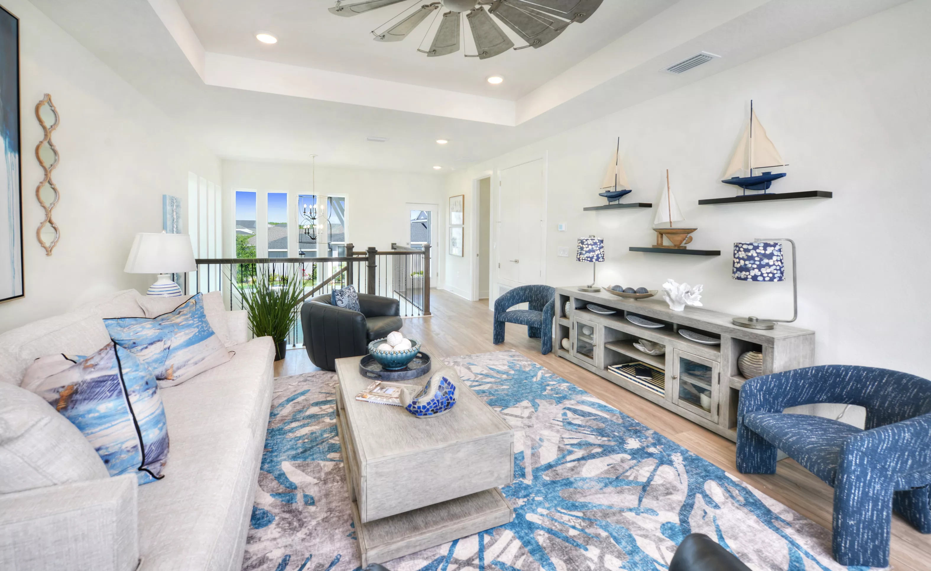 Bonus room in the Azalea plan with a tray ceiling, wood-look flooring, nautical decor, and views of a stairway landing.