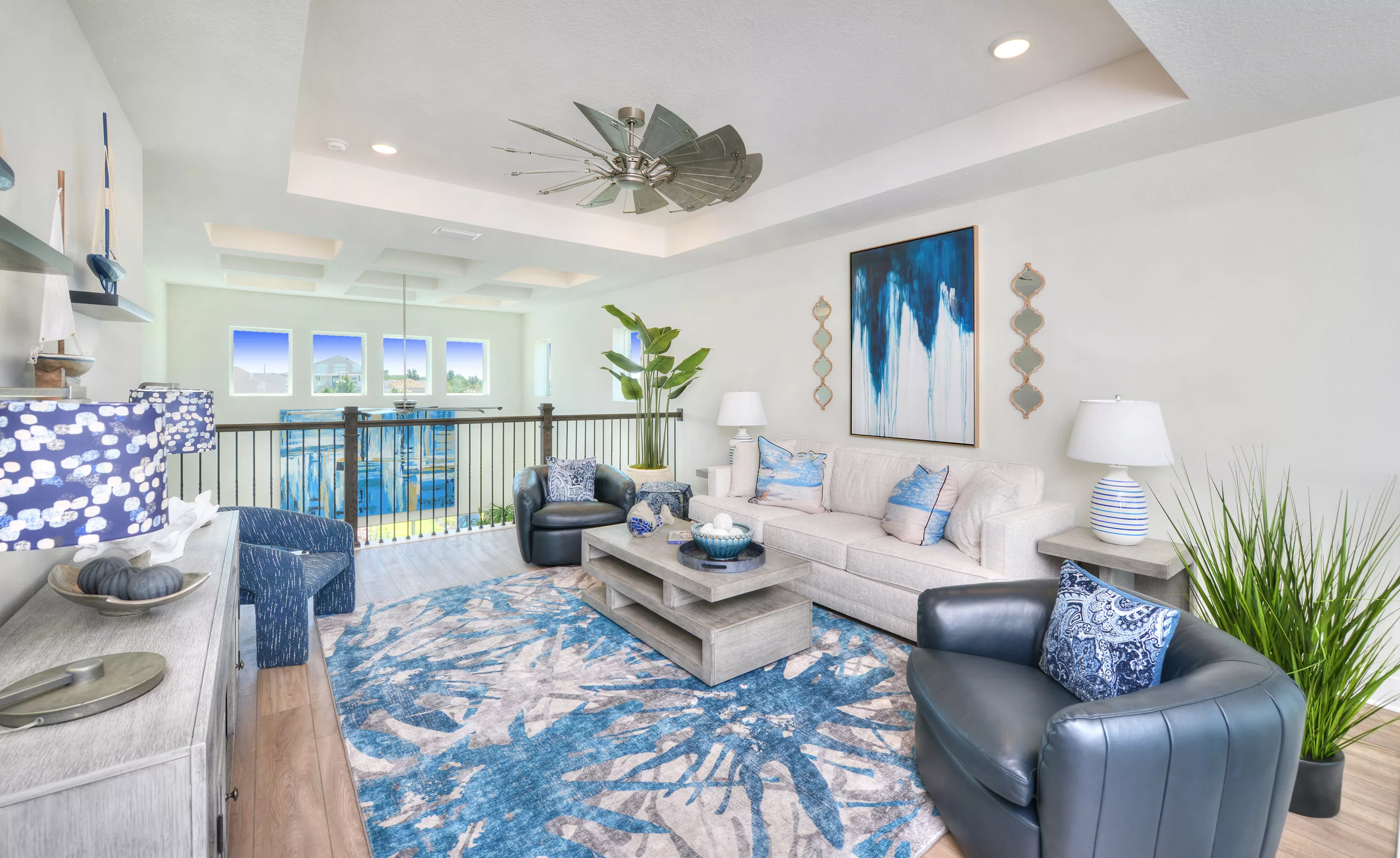 Bonus room in the Azalea plan featuring a tray ceiling, windmill ceiling fan, and open metal railings overlooking a foyer.