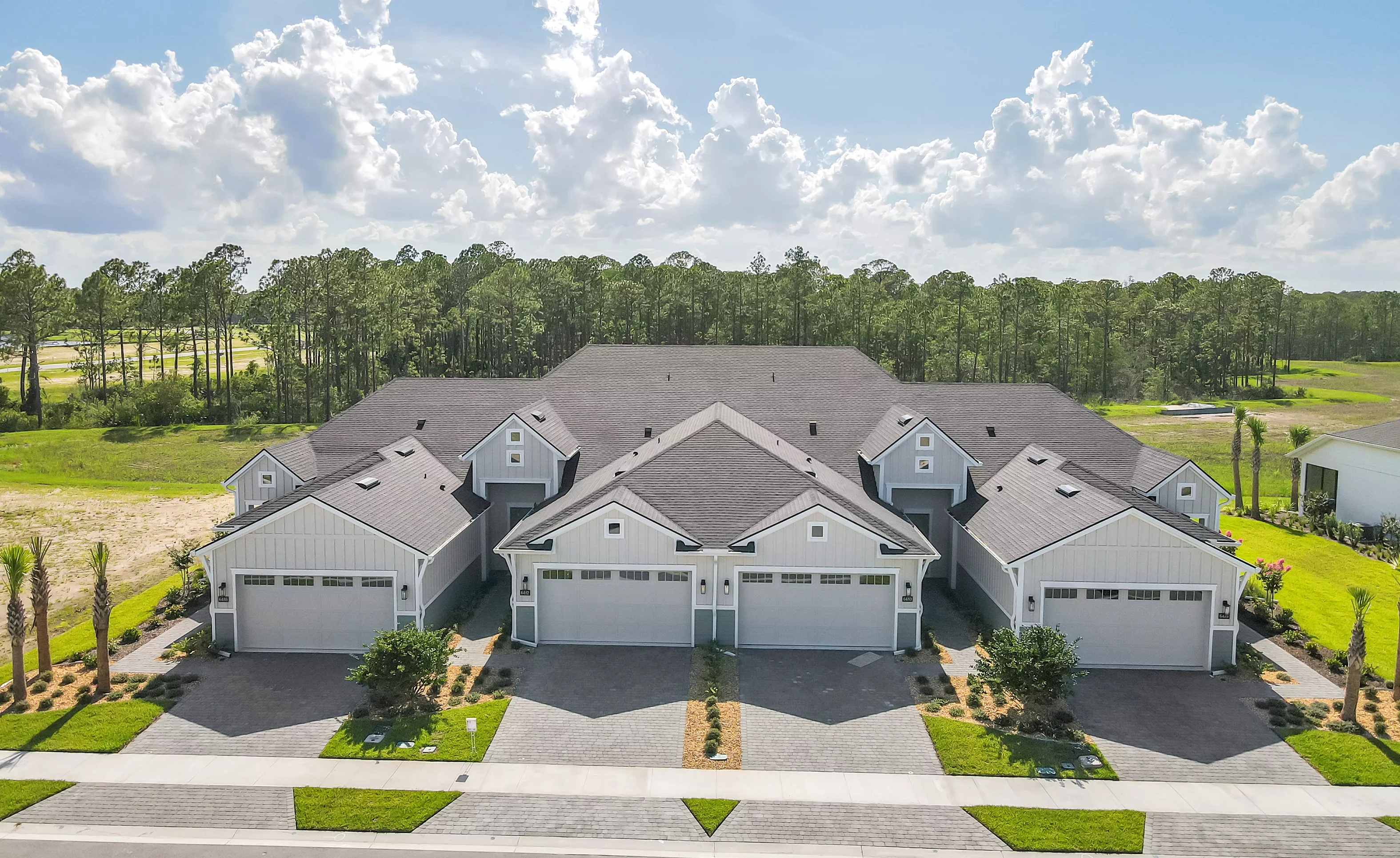 Aerial view of a multi-unit Blossom II building in Woodhaven with gray vertical siding, dark shingled roofs, and garages.