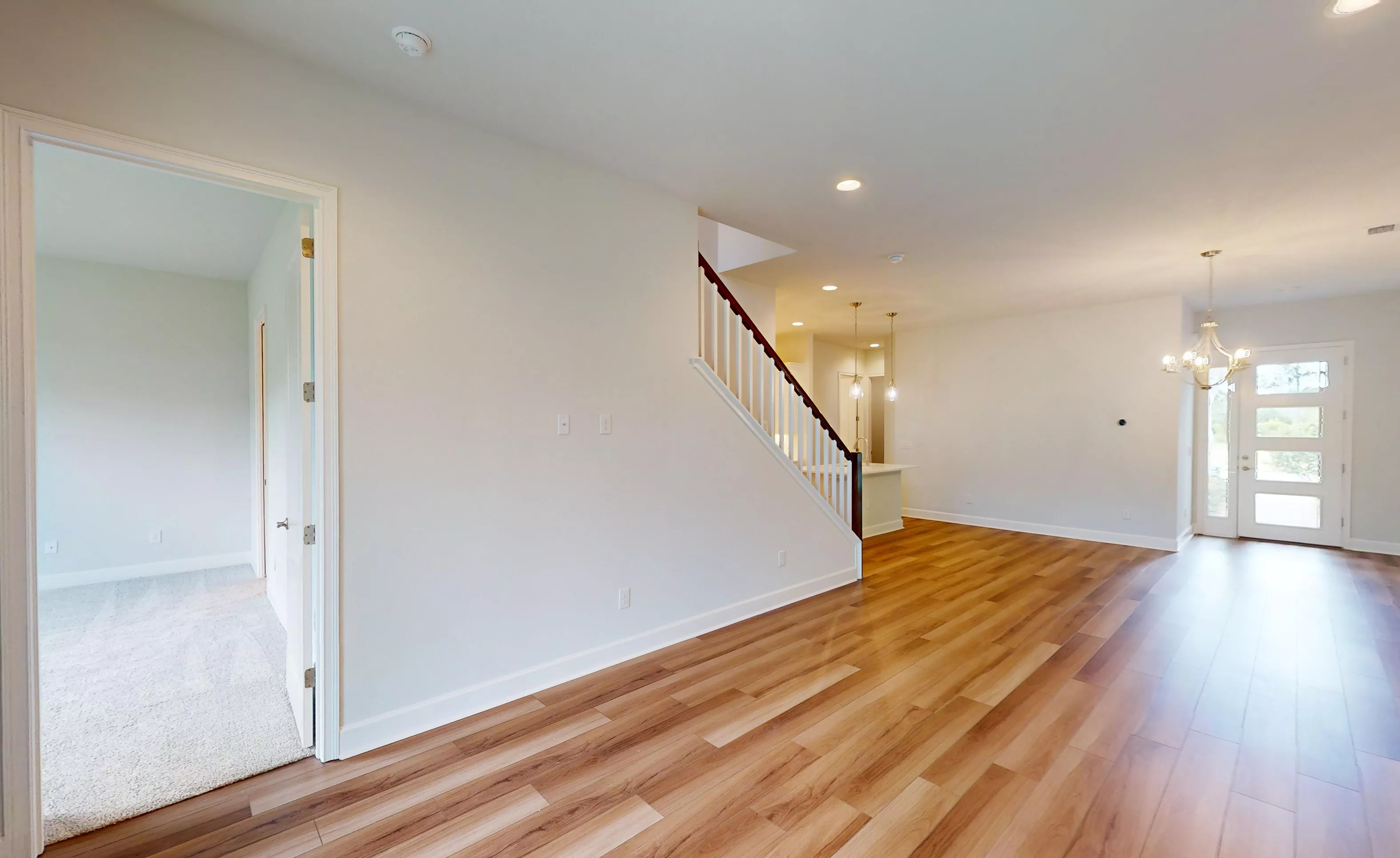 Foyer of the Blossom II plan with wood-look flooring, a staircase with white balusters, and a glass-paneled front door.