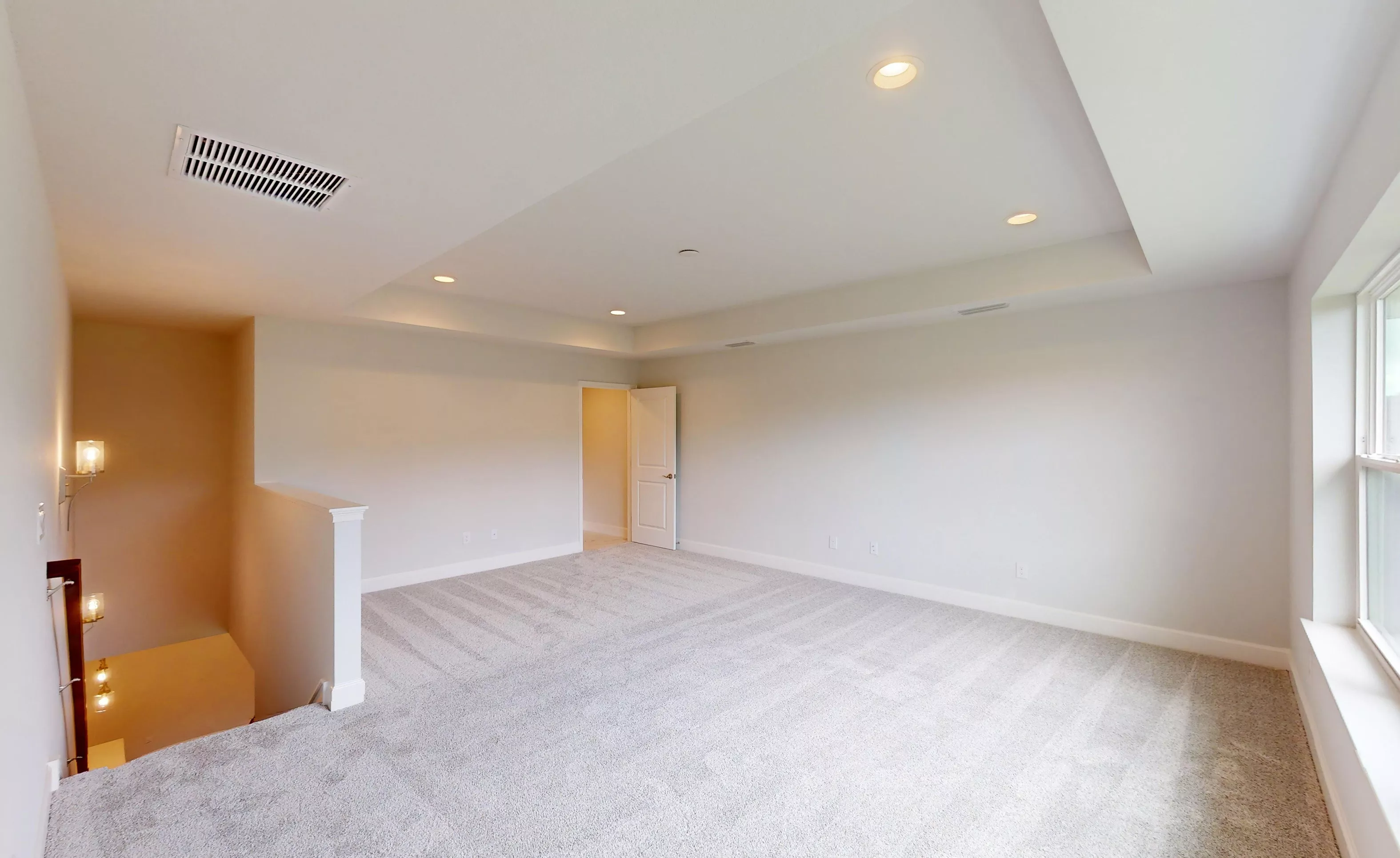 Spacious carpeted bonus room with a tray ceiling, recessed lighting, and a window overlooking an open stairwell.