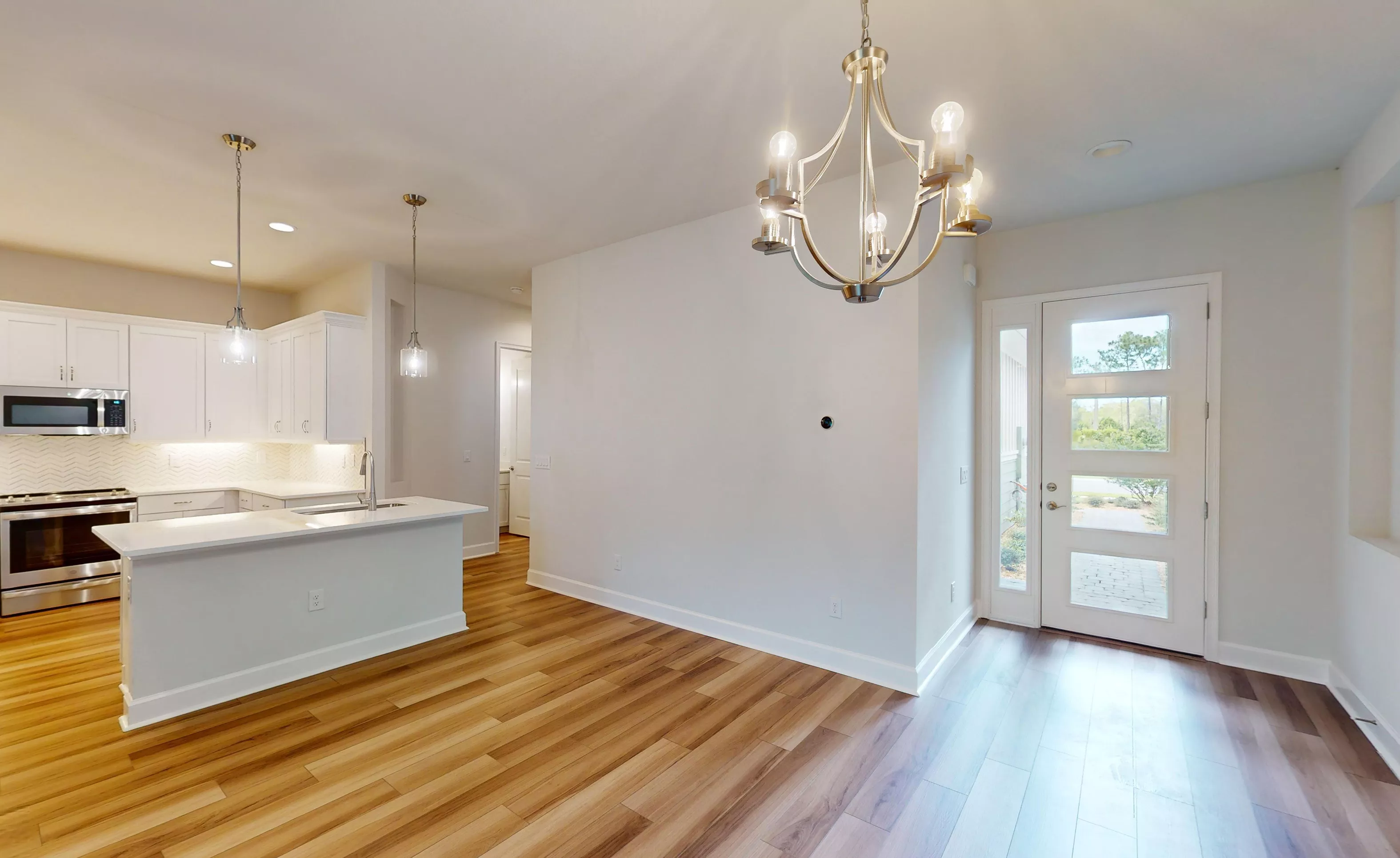 Entryway of the Blossom II home featuring wood-look flooring, a modern chandelier, and an adjacent open-concept kitchen.