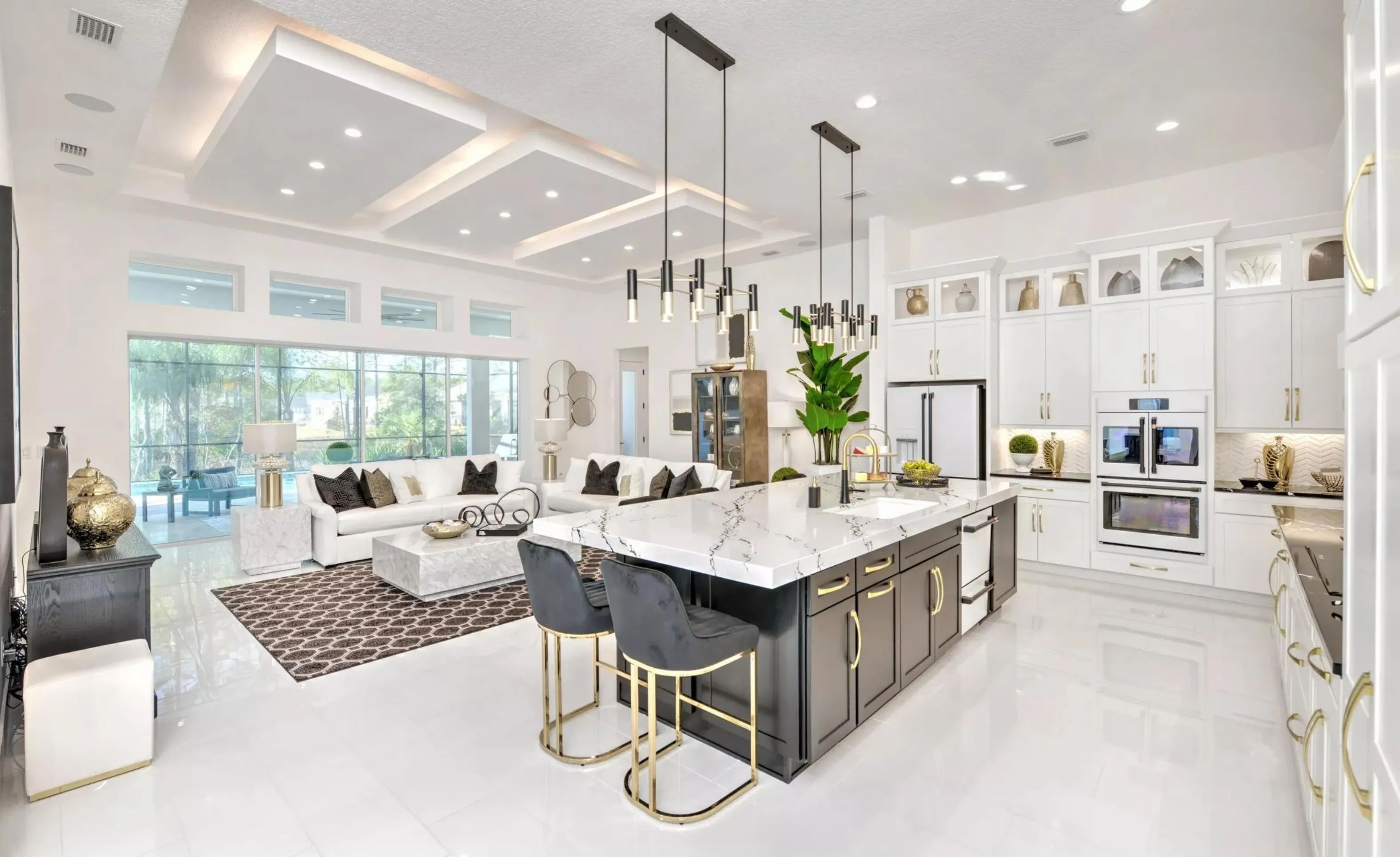 Open-concept kitchen and living area in Woodhaven featuring a black island with white marble top and gold stools.