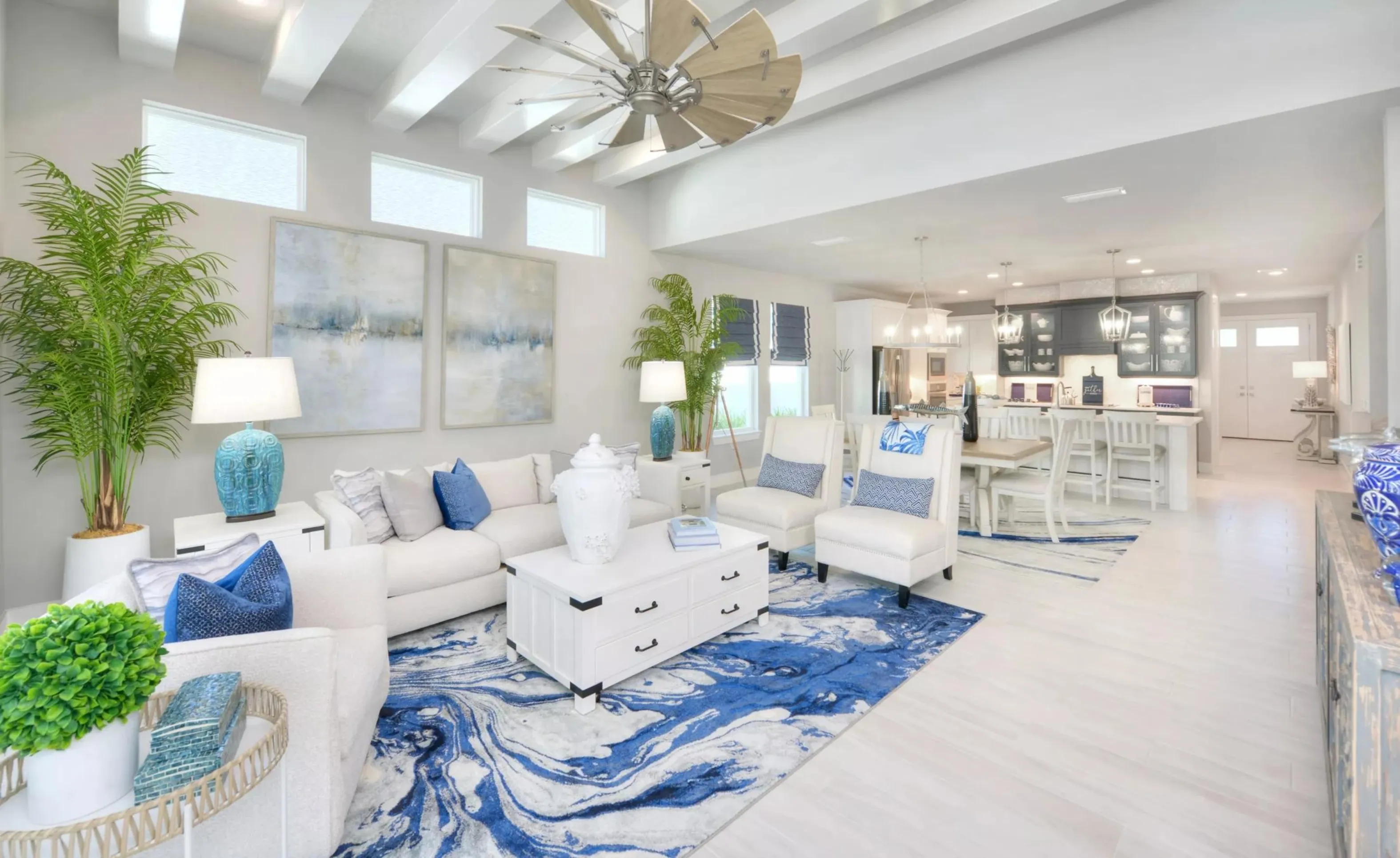 Open-concept living room and kitchen in Woodhaven with coffered ceilings, windmill fan, white furniture, and blue accents.