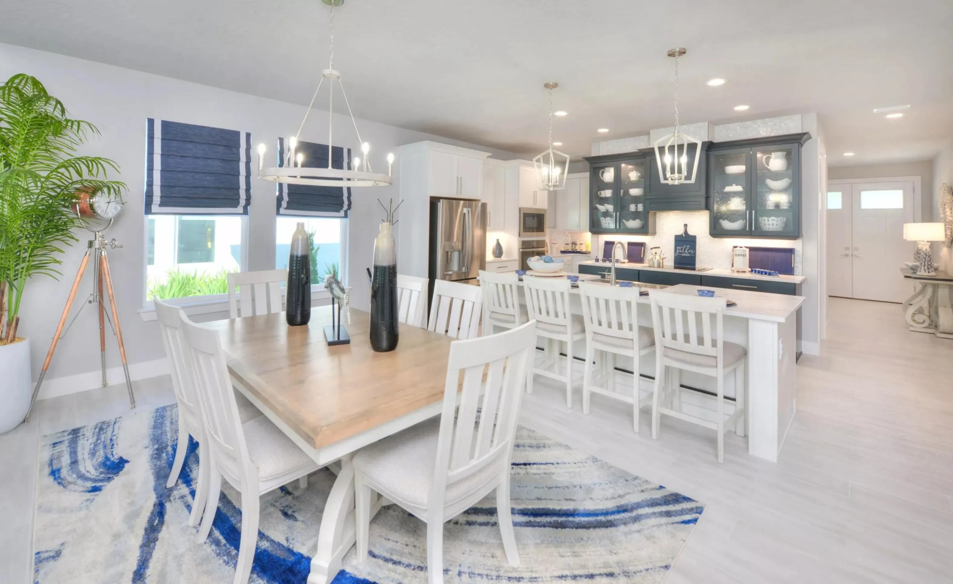Open dining and kitchen area in Woodhaven featuring white cabinetry, a kitchen island, and a light wood dining table.