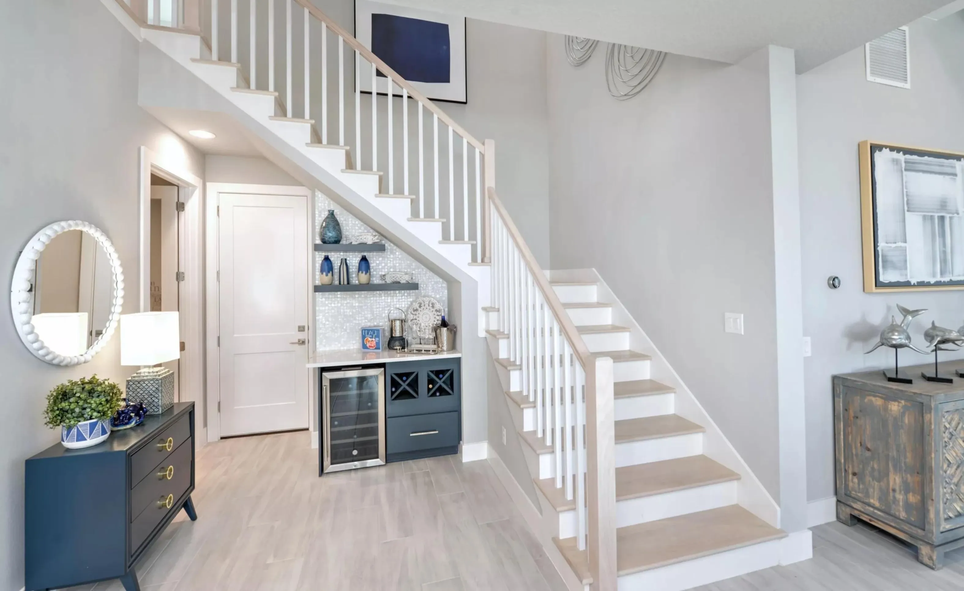 Staircase in a Woodhaven home with white railings, light wood treads, and a built-in wet bar with wine cooler underneath.