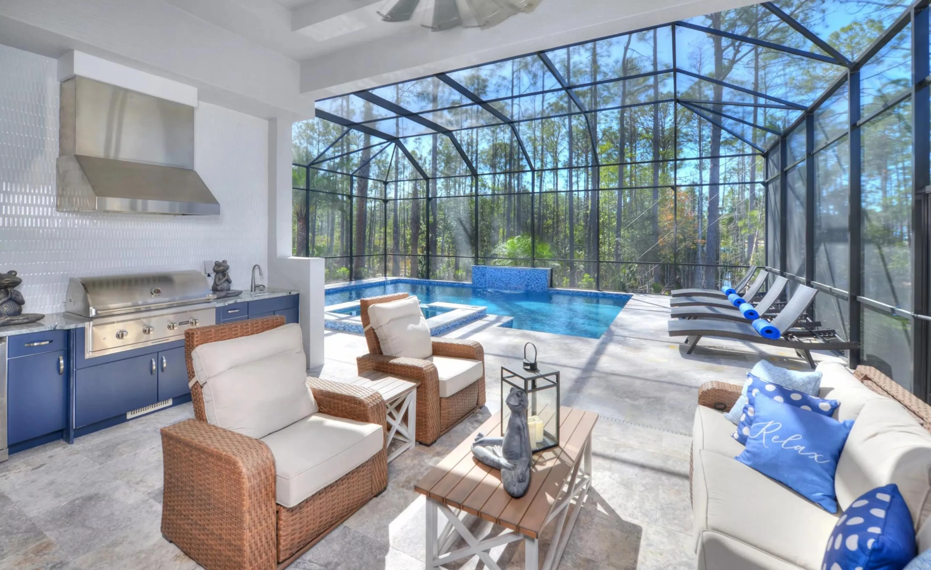 Screen-enclosed patio in Woodhaven featuring an outdoor kitchen, pool, spa, and comfortable wicker furniture.
