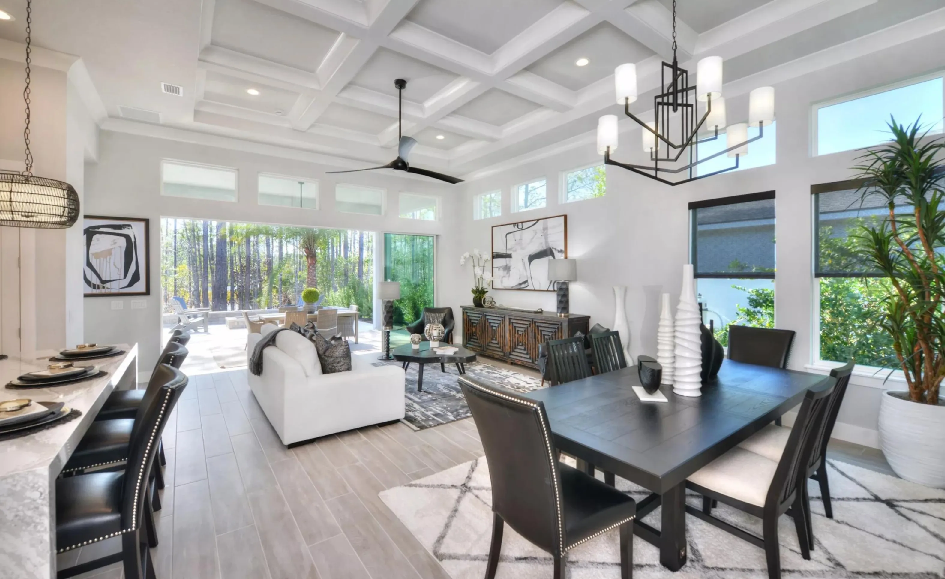 Open-concept living and dining area in Woodhaven with coffered ceilings, tile floors, and large glass sliding doors.