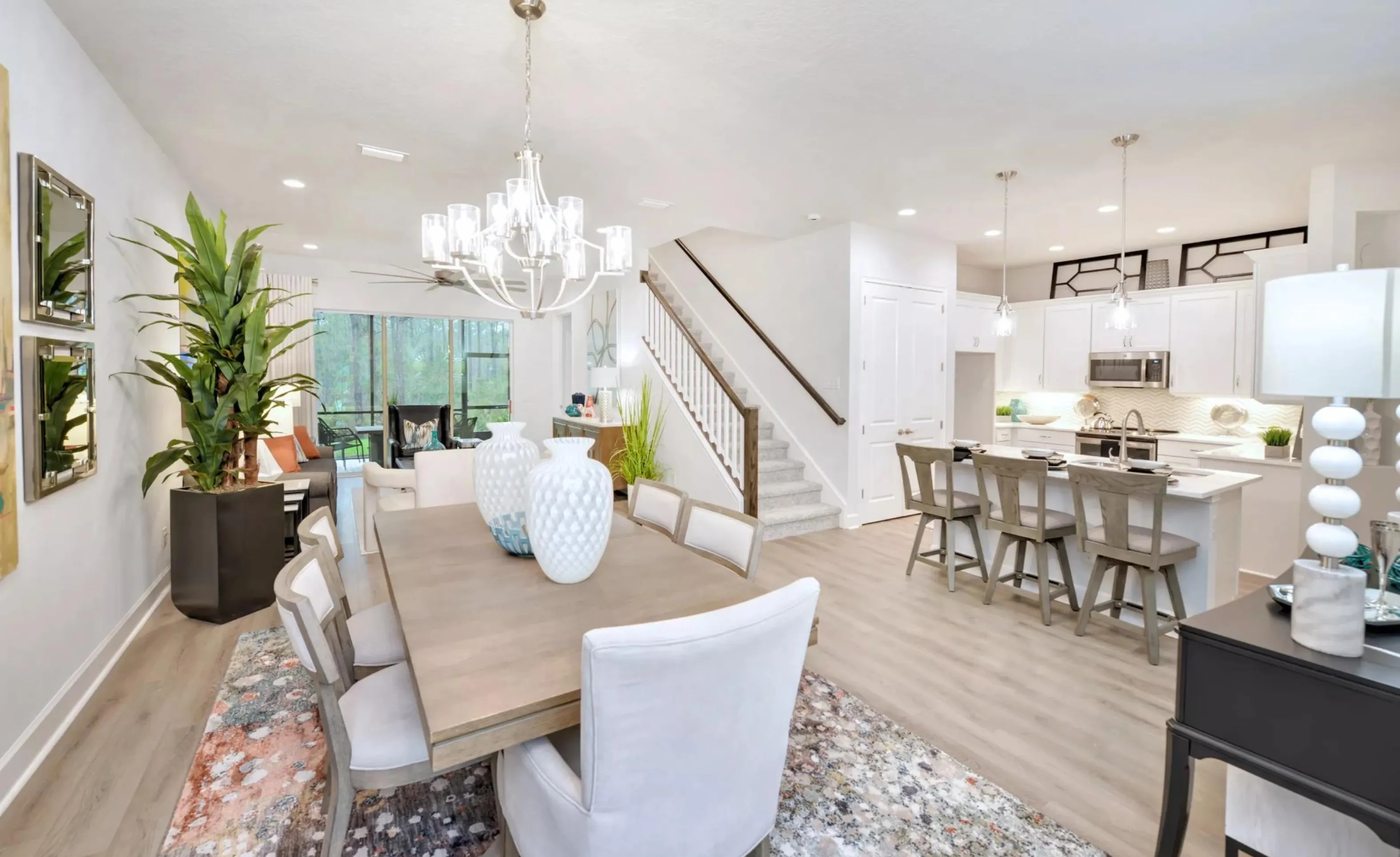 Open-concept Woodhaven home with dining area, staircase, and kitchen featuring white cabinetry and a center island.