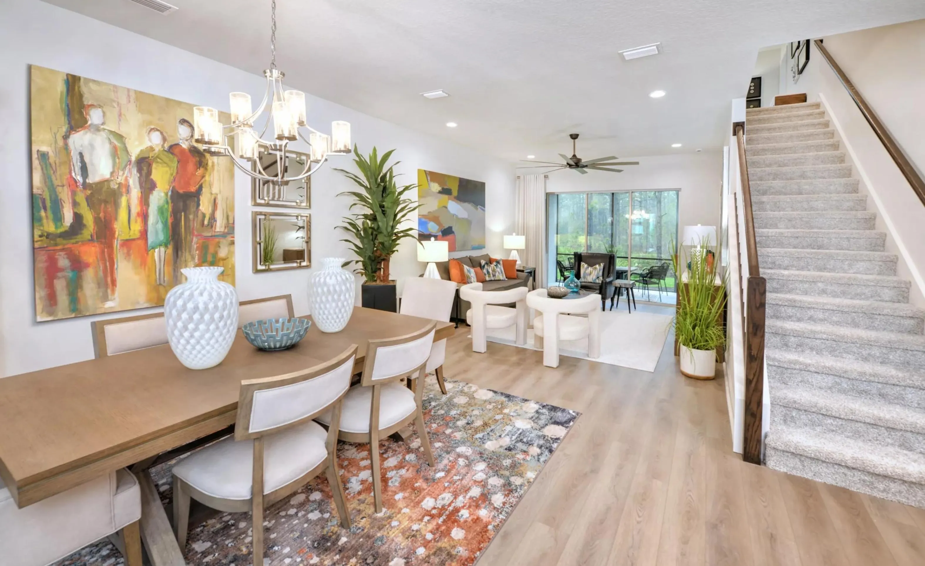 Open-concept dining and living area in a Woodhaven home with hardwood floors, a staircase, and view of the patio.