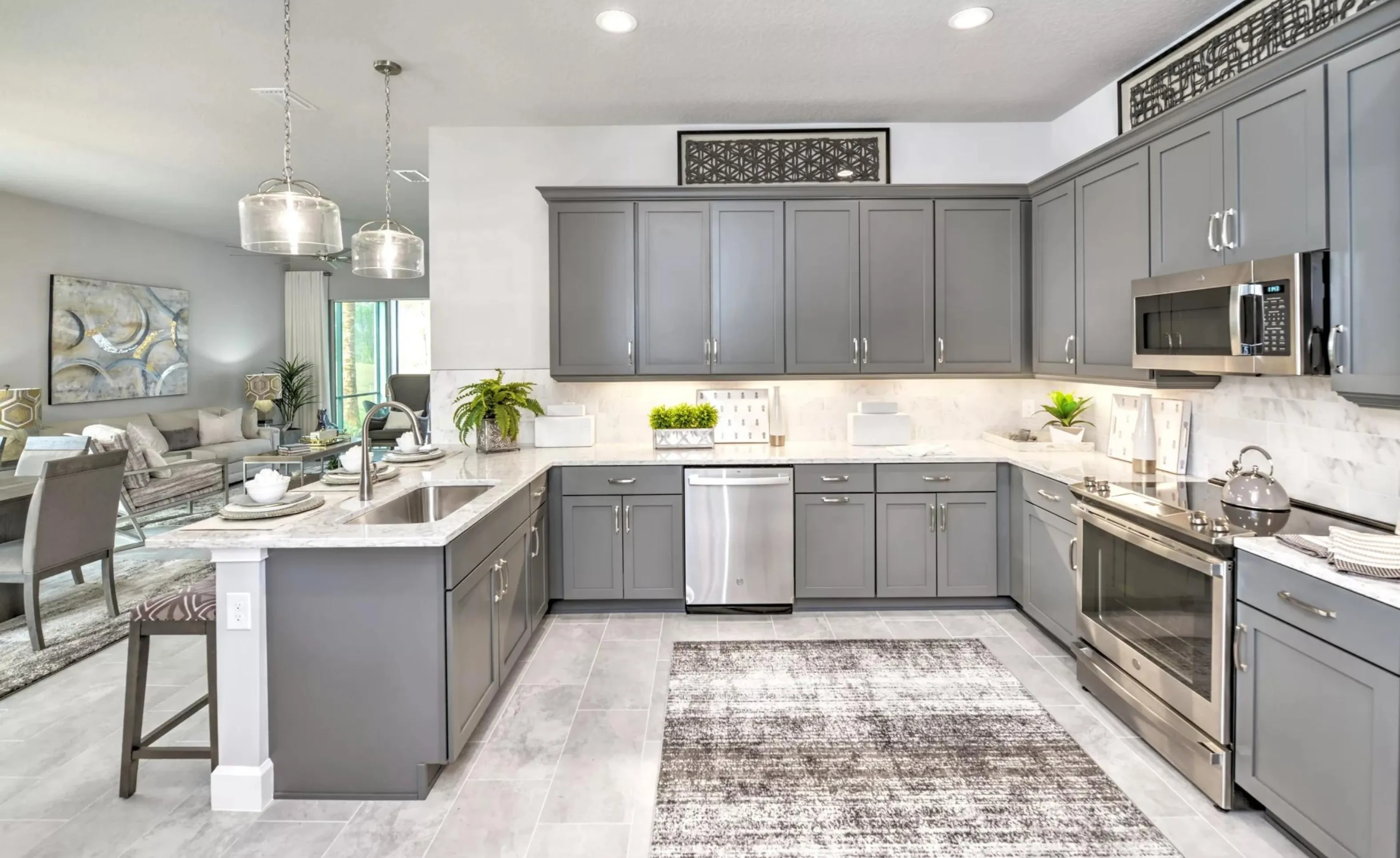 Modern kitchen in Woodhaven with gray cabinetry, stainless steel appliances, white marble-style counters, and tile floors.