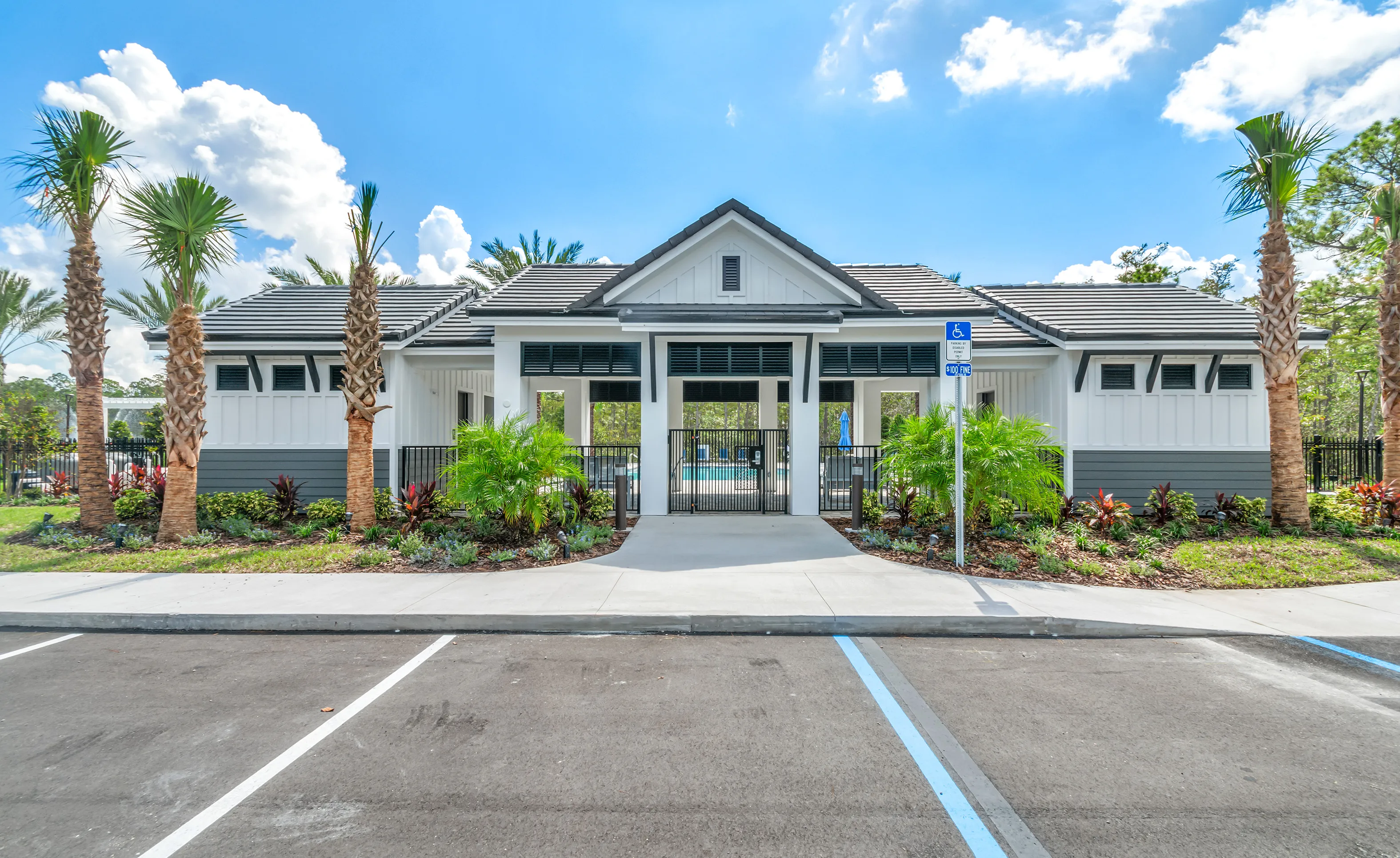 The Woodhaven community pool building features white board-and-batten siding, a dark gabled roof, and a gated entrance.