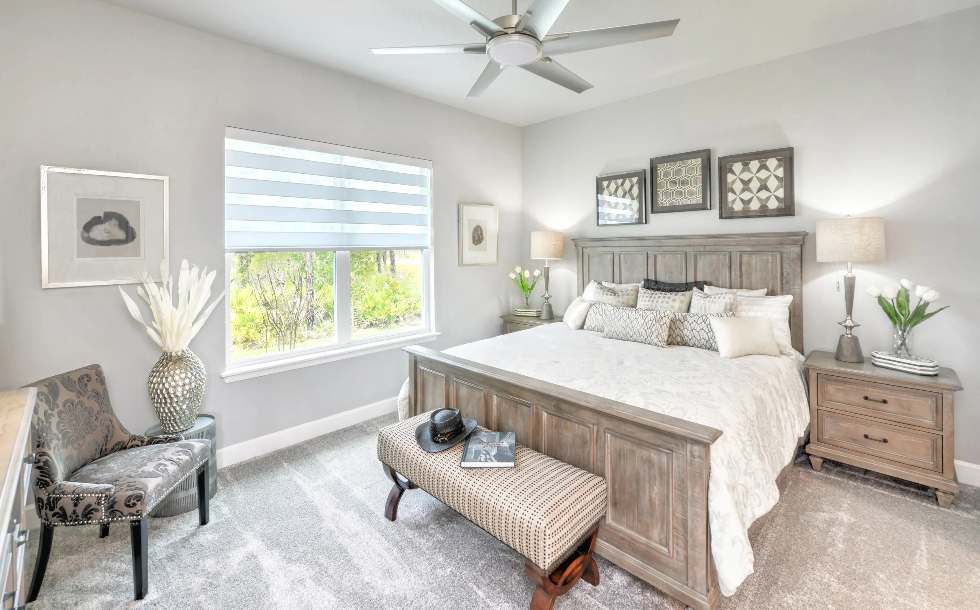 Bedroom in Woodhaven Townhomes with light gray walls, carpet, wooden bed frame, matching nightstands, and window view.