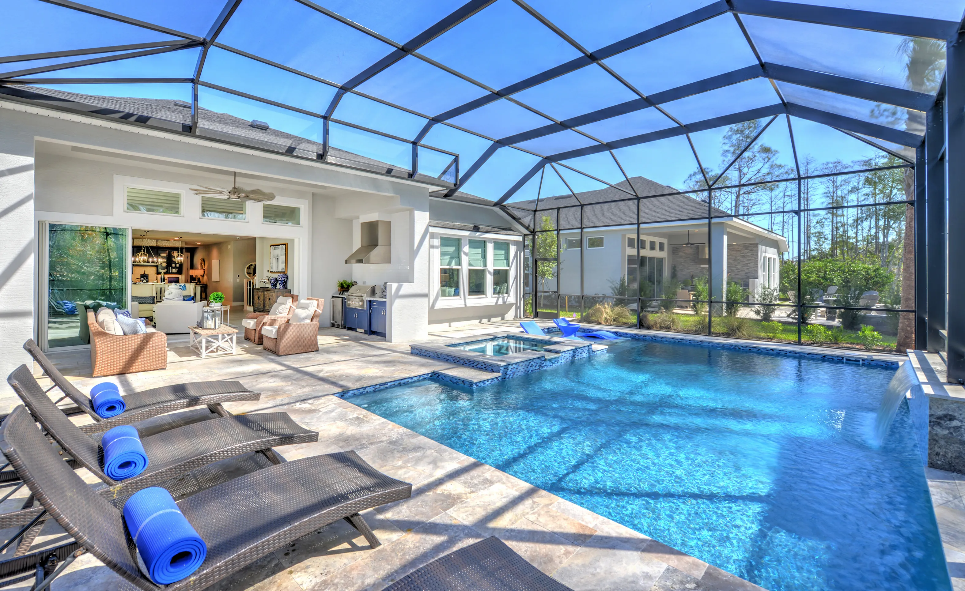 Screened-in pool patio at Woodhaven Single Family with lounge chairs, integrated spa, outdoor kitchen, and sliding doors.