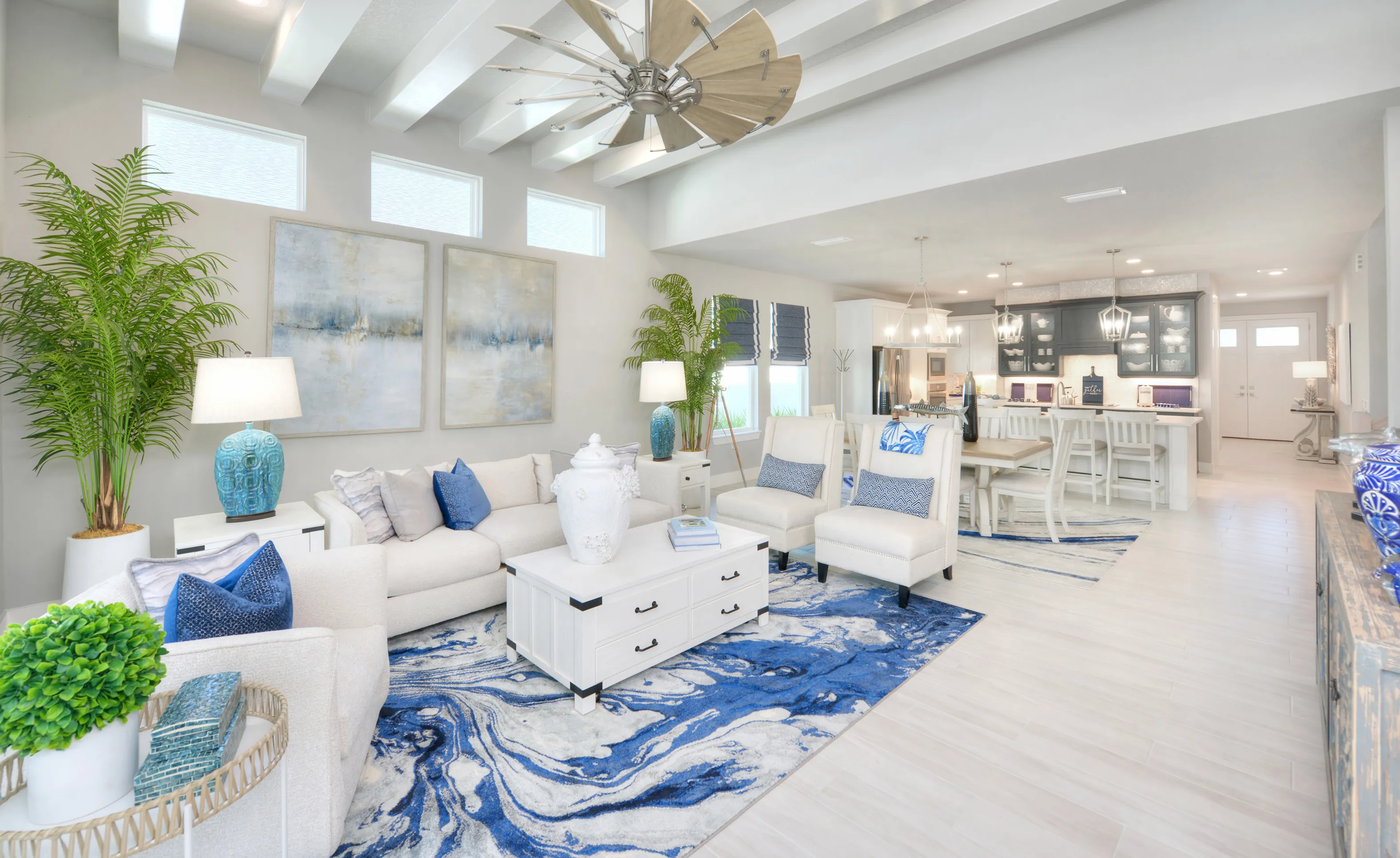 Open floor plan living area at Woodhaven Single Family with a beamed ceiling, large fan, and blue and white decor.