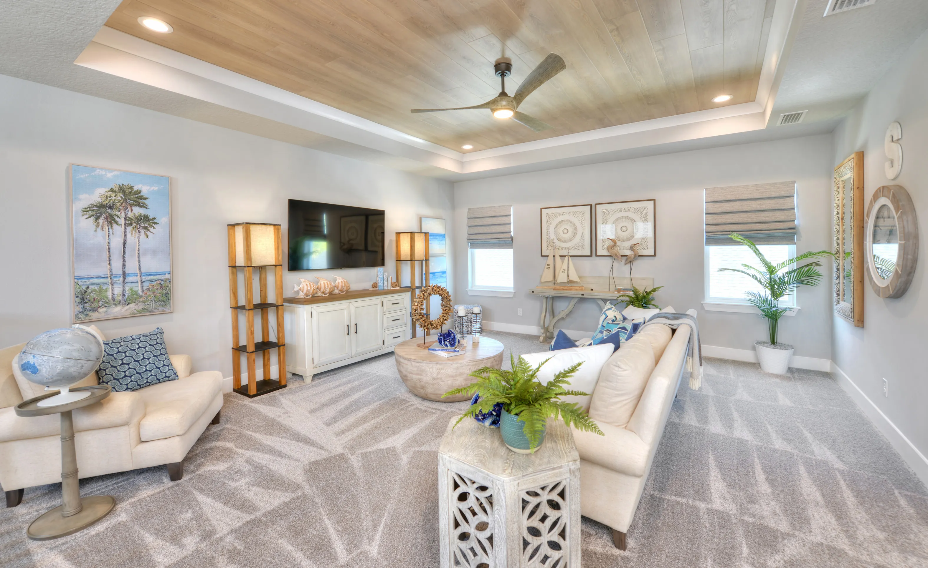 Living room in a Woodhaven home featuring a wood-plank tray ceiling, white media console, and neutral furniture.