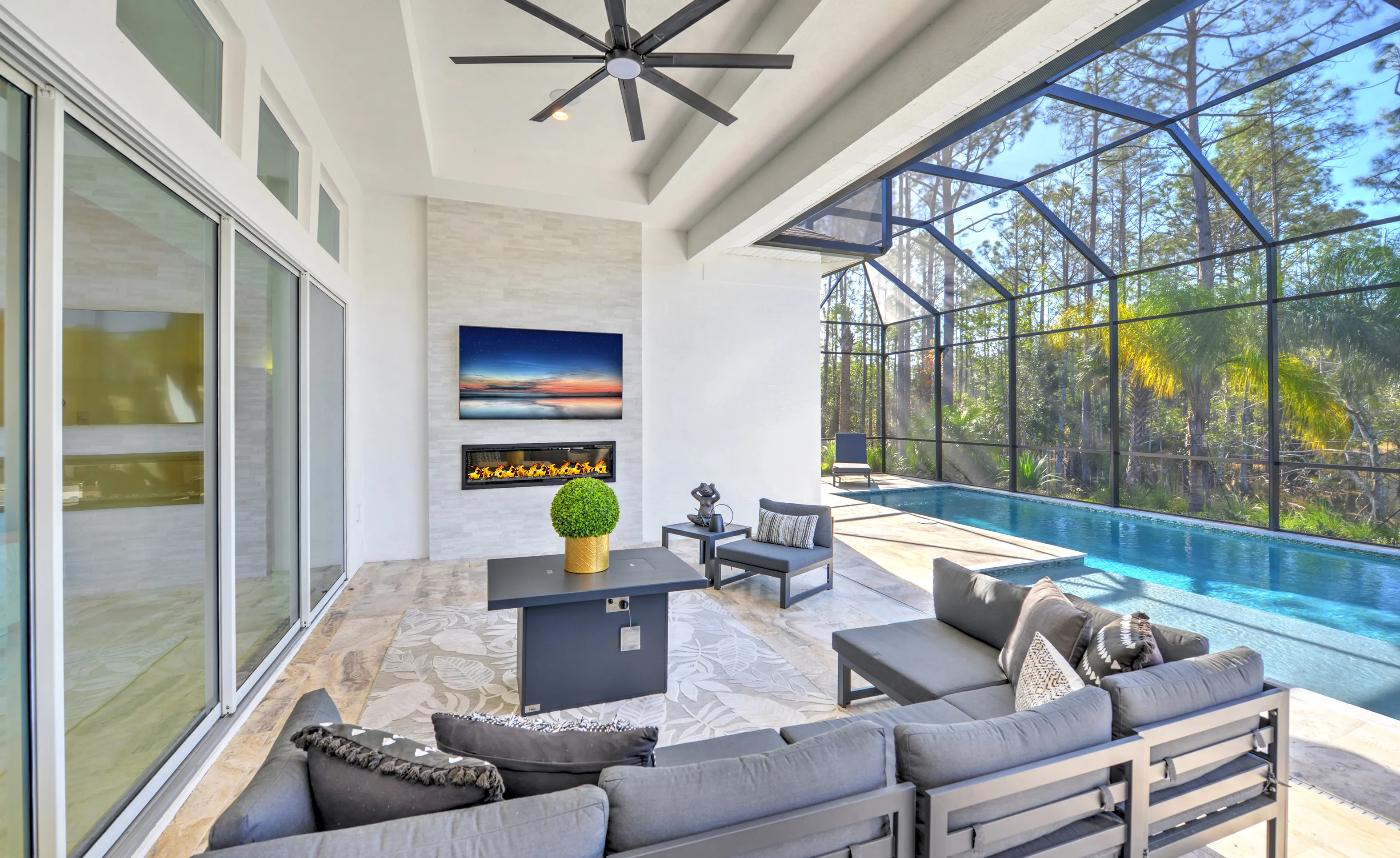 Covered patio at Woodhaven Single Family with a stone fireplace, wall-mounted television, and a screened-in pool.