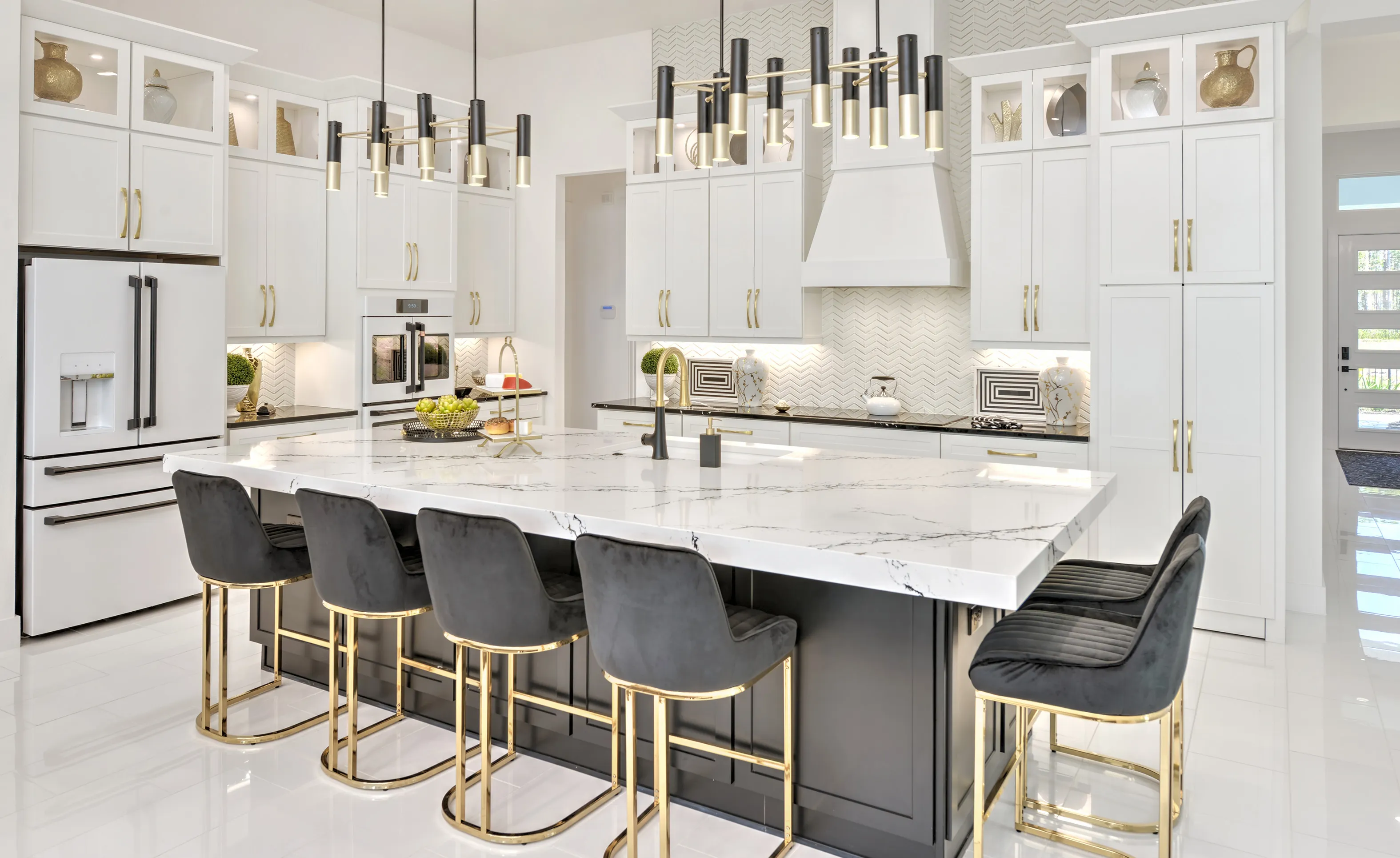 Modern kitchen with a black island, white cabinets, marble countertops, and black bar stools with gold accents.