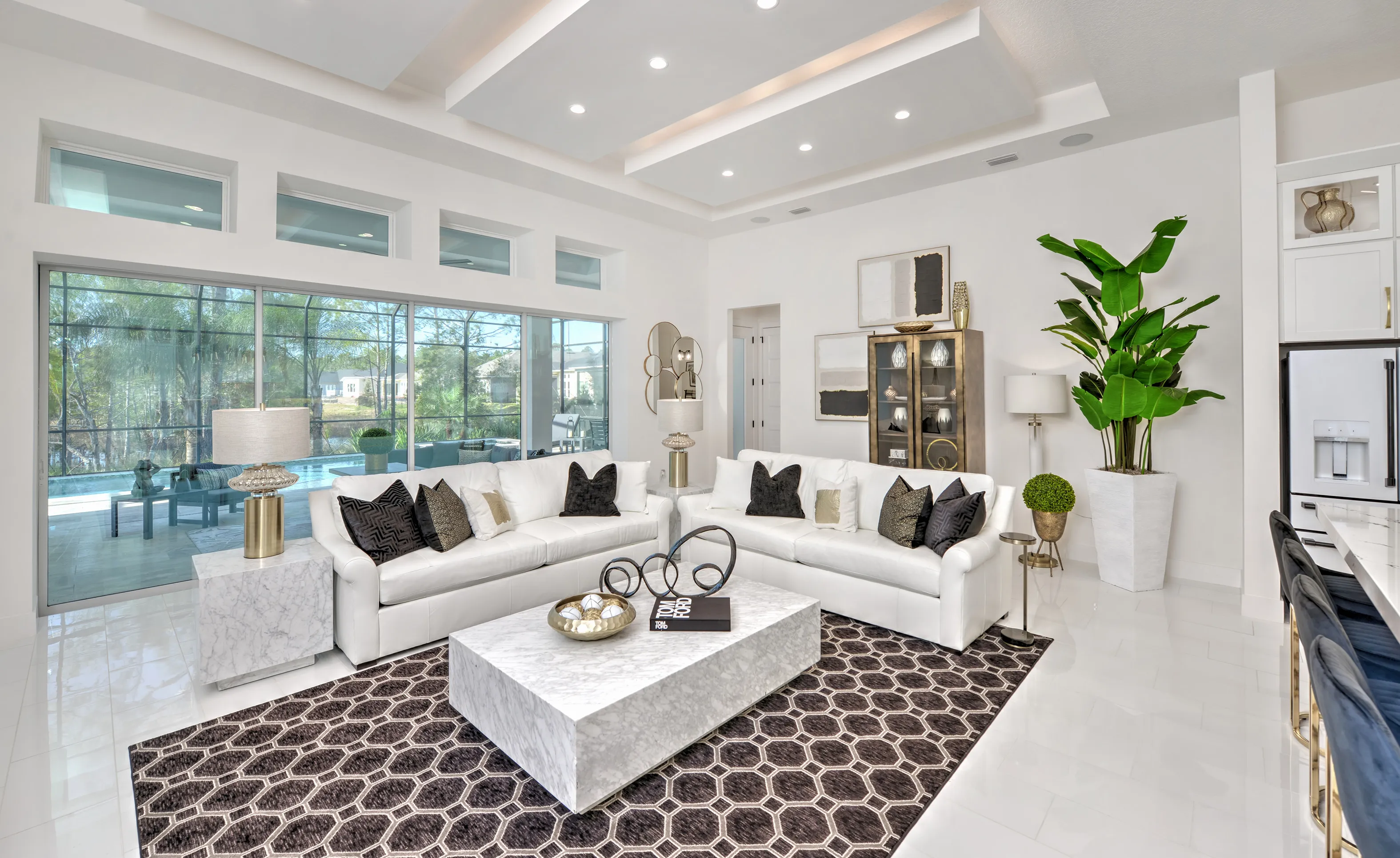 Living room in Woodhaven Single Family home with tray ceiling, white sofas, marble coffee table, and large sliding doors.