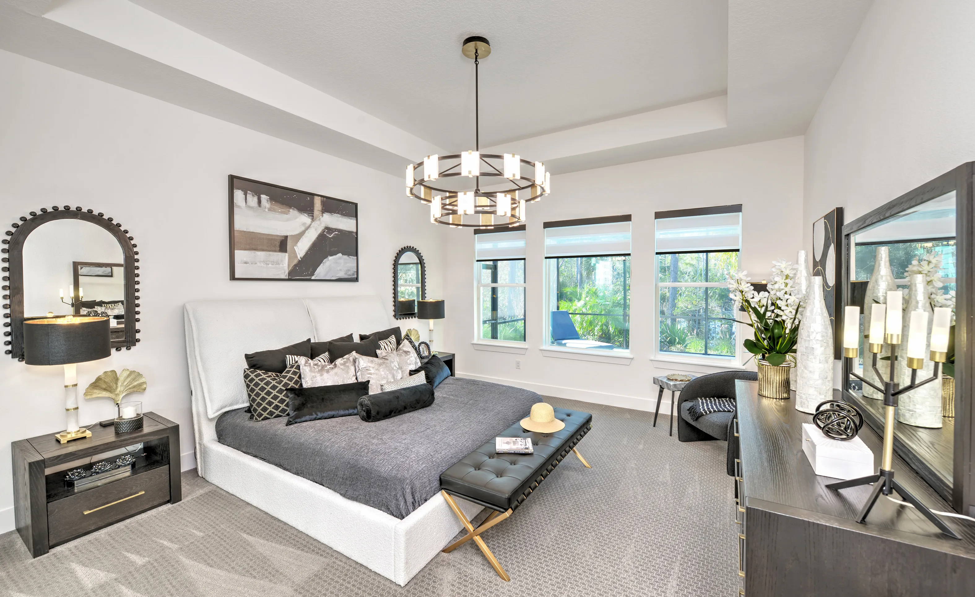 Woodhaven Single Family bedroom with white upholstered bed, modern chandelier, coffered ceiling, and gray carpet.