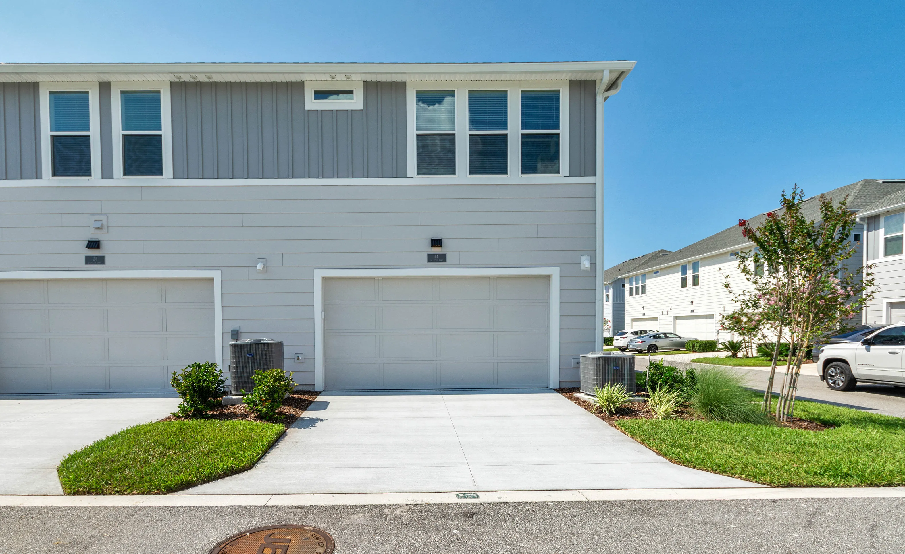 Side view of a two-story home with light gray horizontal siding, a two-car garage, and a concrete driveway.